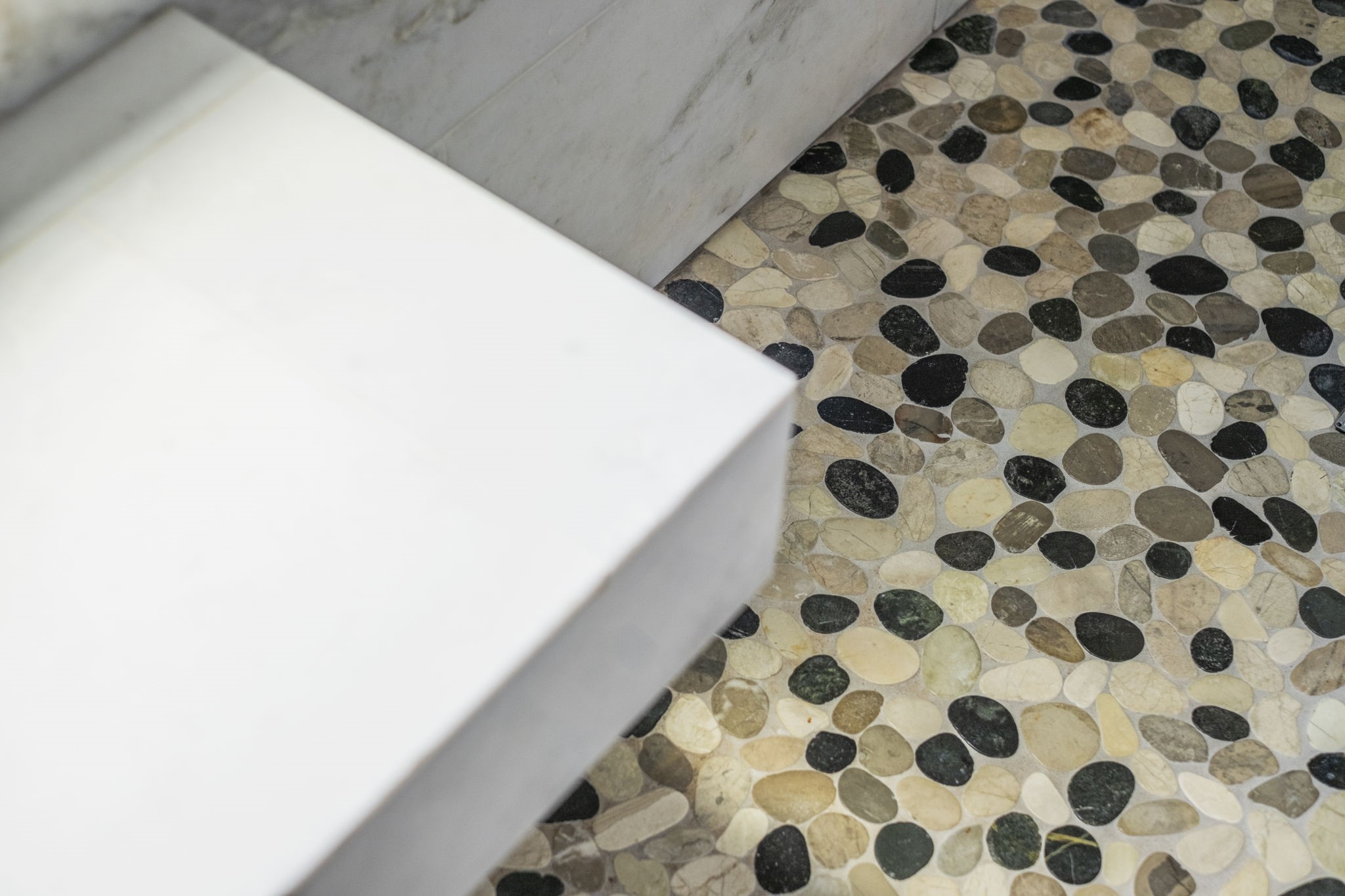 Pebble stone floor adds a spa-like touch to this luxurious primary bathroom.