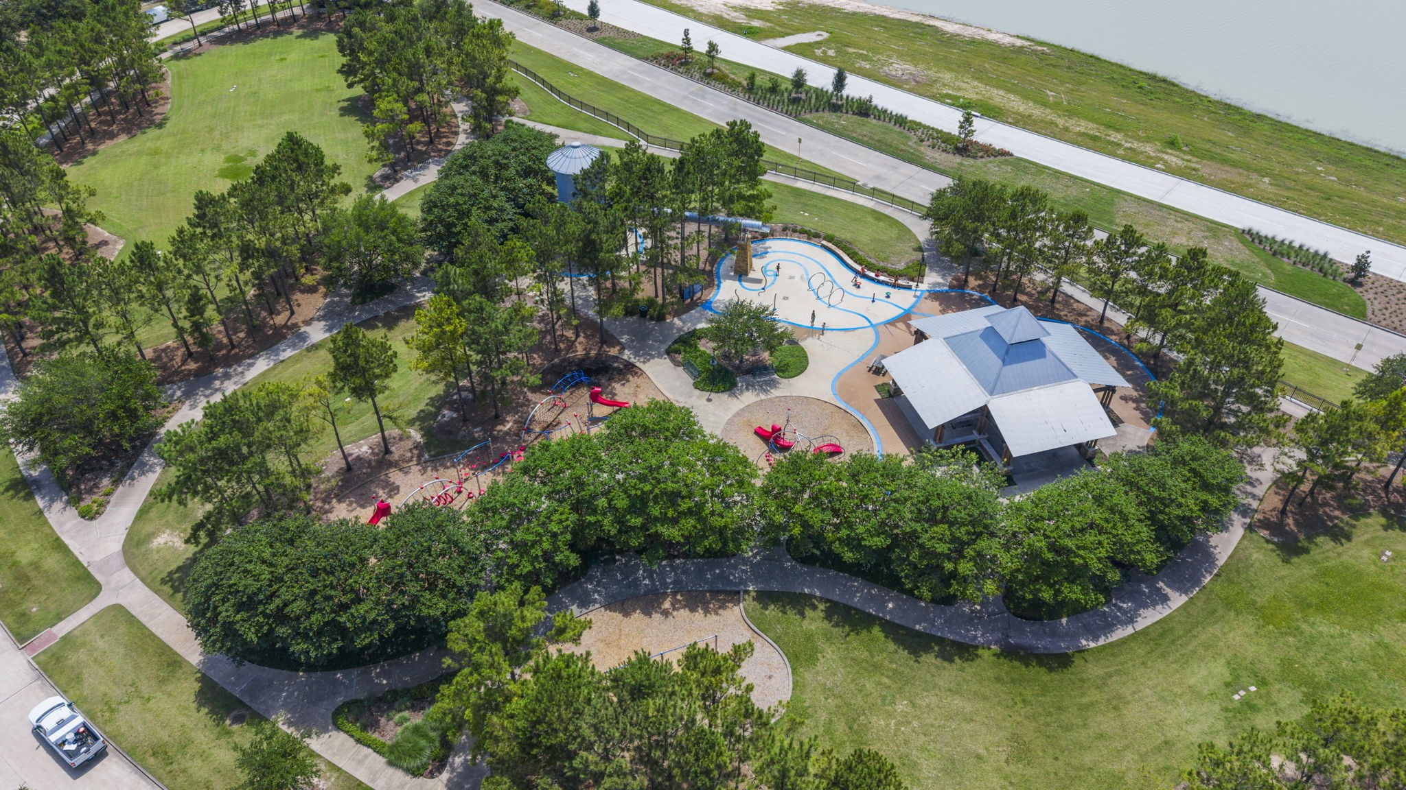 This is the lovely scenic park in front of the home with lush greenery, a winding pathway, & a vibrant playground area.