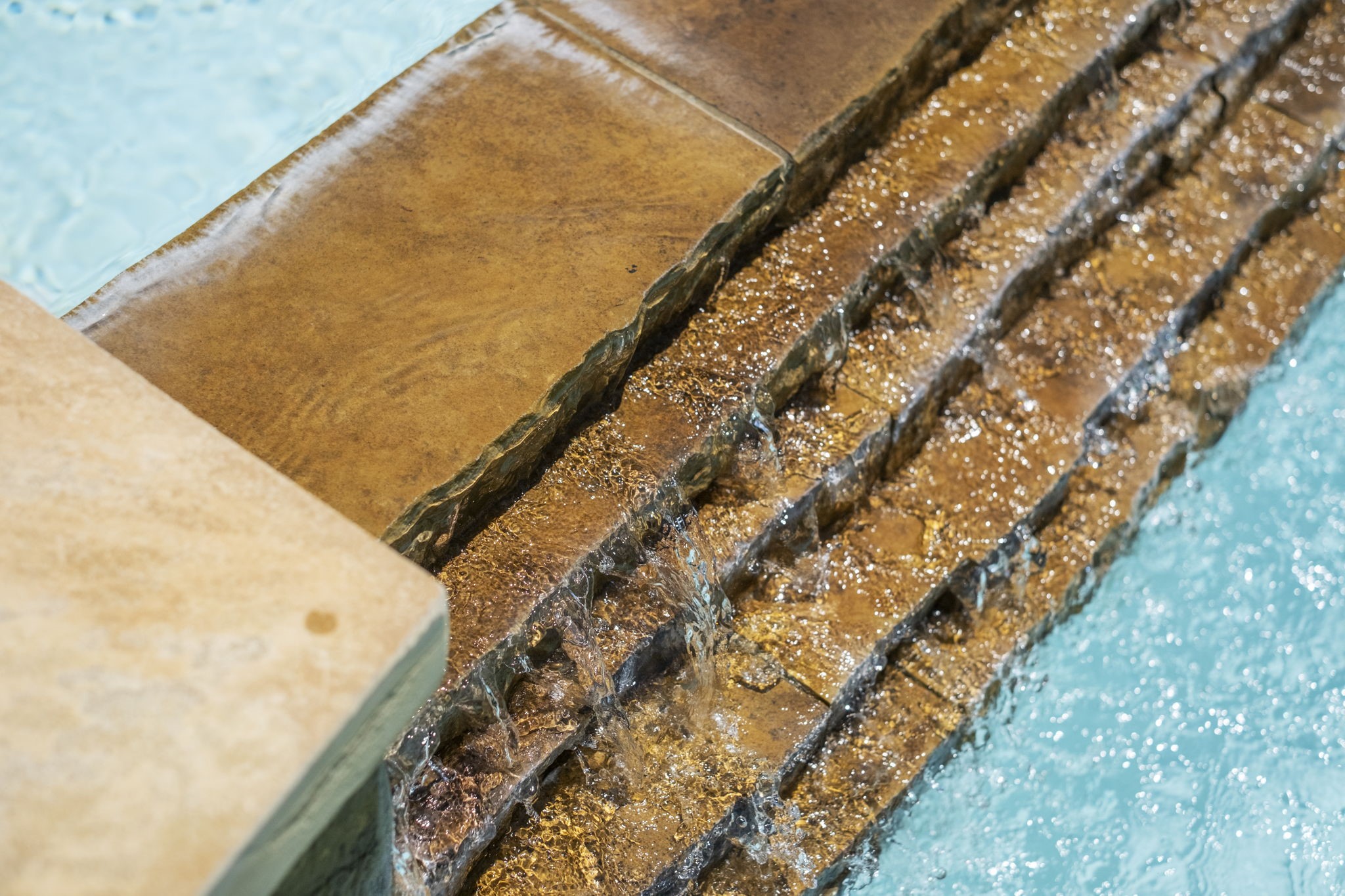 Beautiful water feature with cascading stacked stone leading into the pool, offering a serene and elegant touch to the outdoor space.