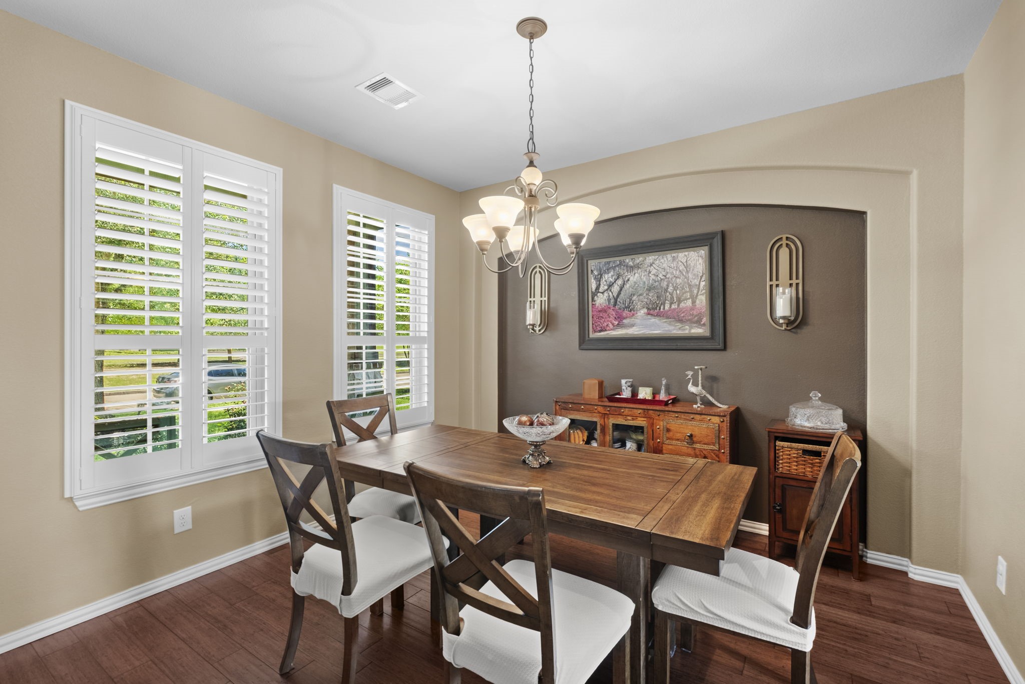 Elegant formal dining room with plantation shutters & wood floors overlook the front yard.
