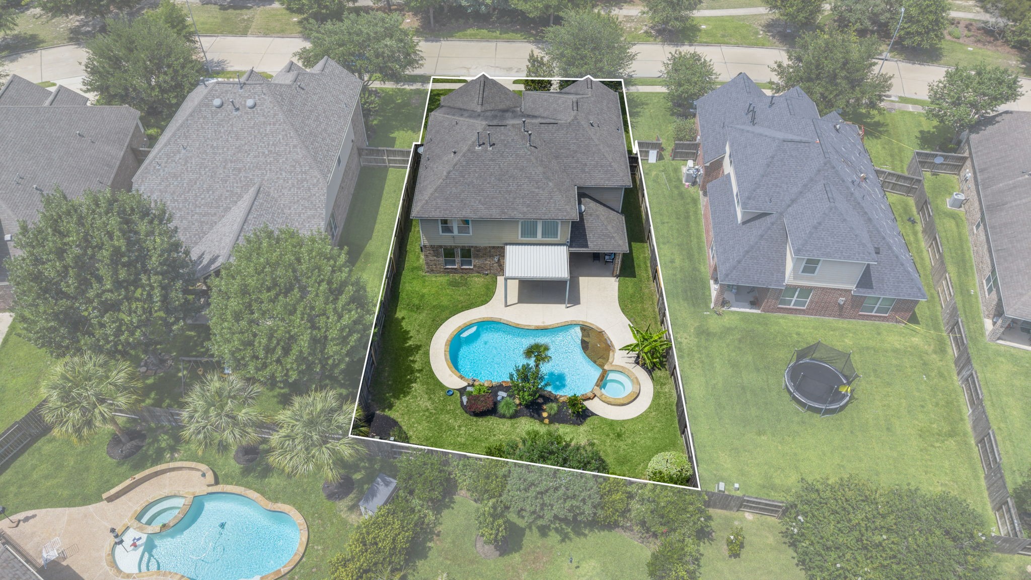 This aerial photo showcases a spacious two-story home with a fenced backyard featuring a pool and spa.