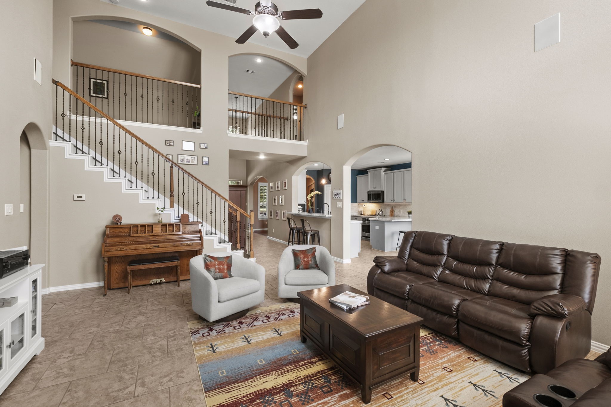 The open layout includes a view of the kitchen and dining area, with the staircase leading to an upper level.