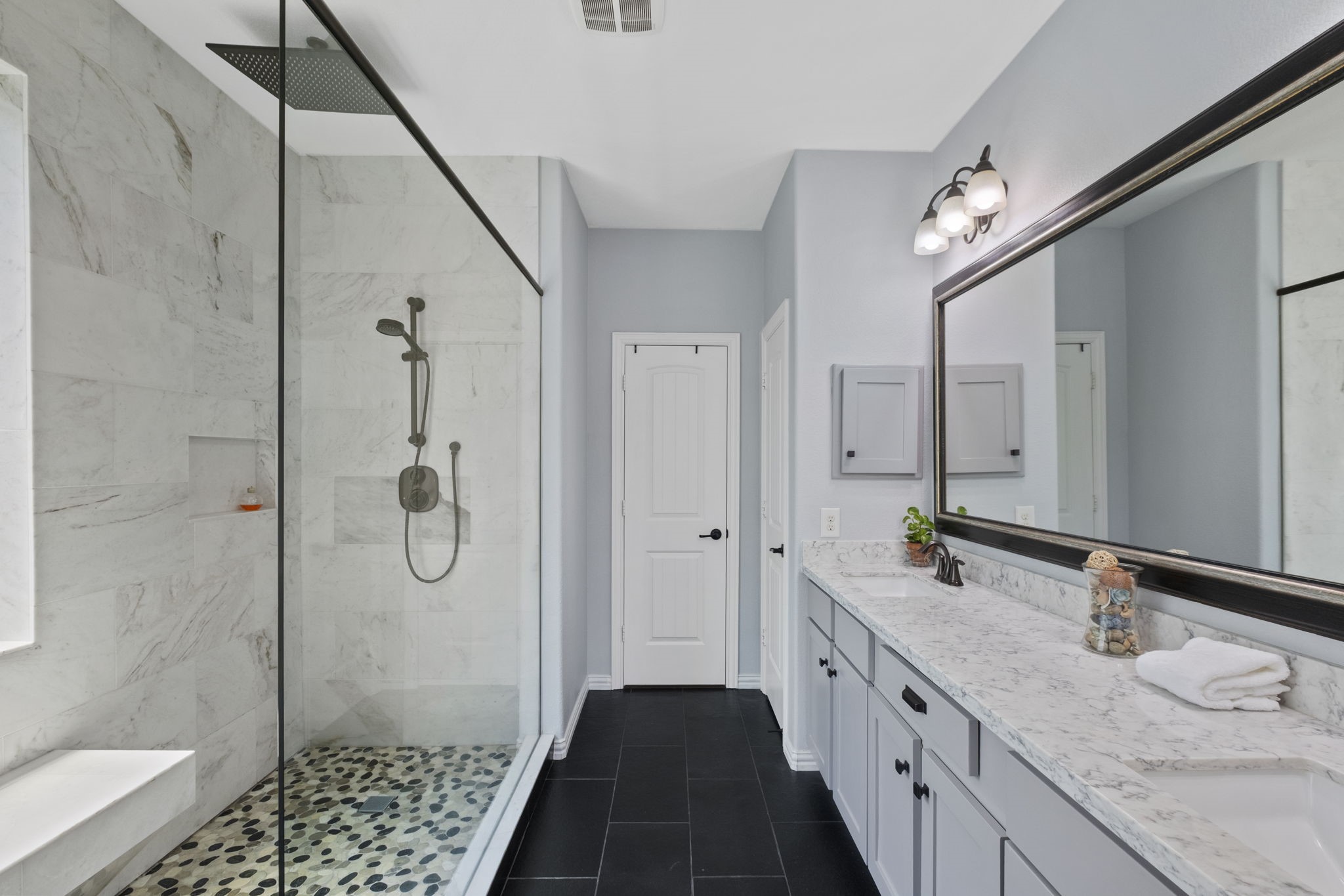 This bathroom features a sleek design with a large glass-enclosed shower, marble-look walls,