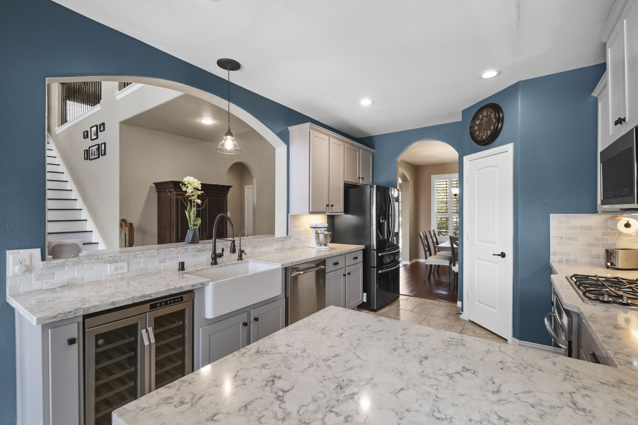 This kitchen features modern amenities with quartz countertops, a farmhouse sink, and stainless steel appliances.