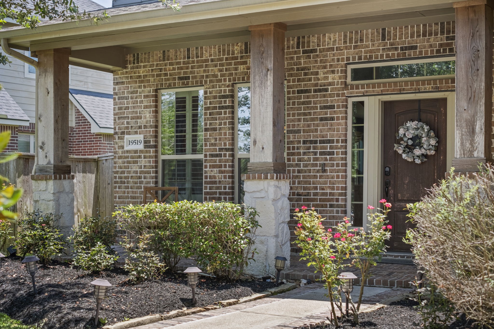 Charming front porch with wood & stone columns add a nice touch to this inviting home.