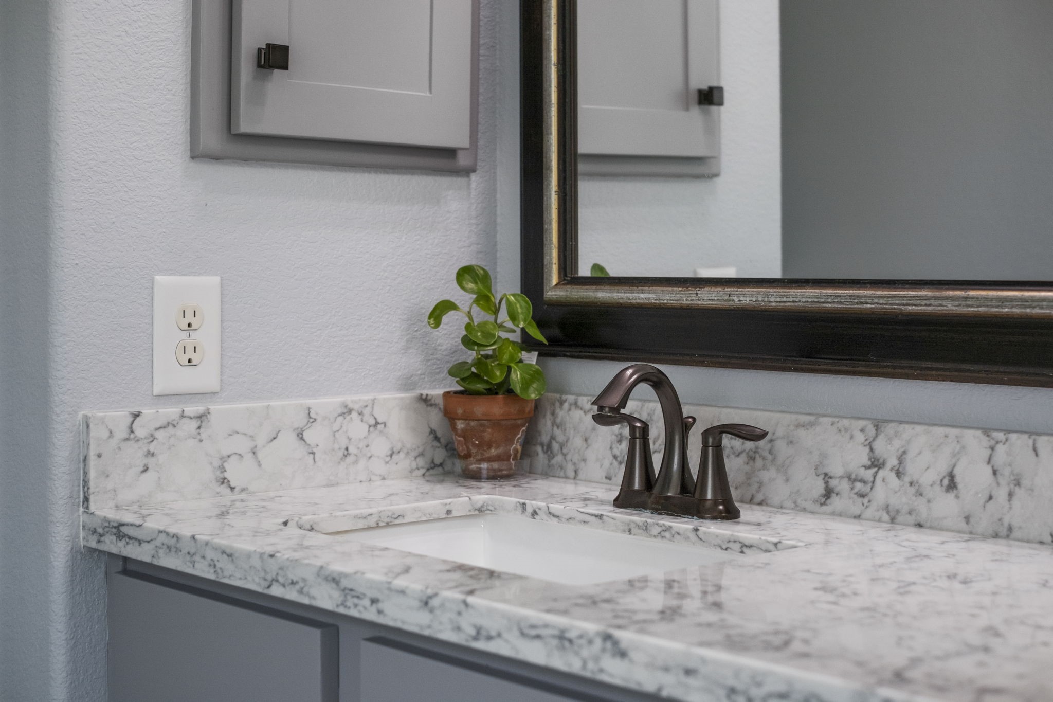 The primary bathroom features a sleek countertop with two under-mounted sinks and elegant bronze faucets.