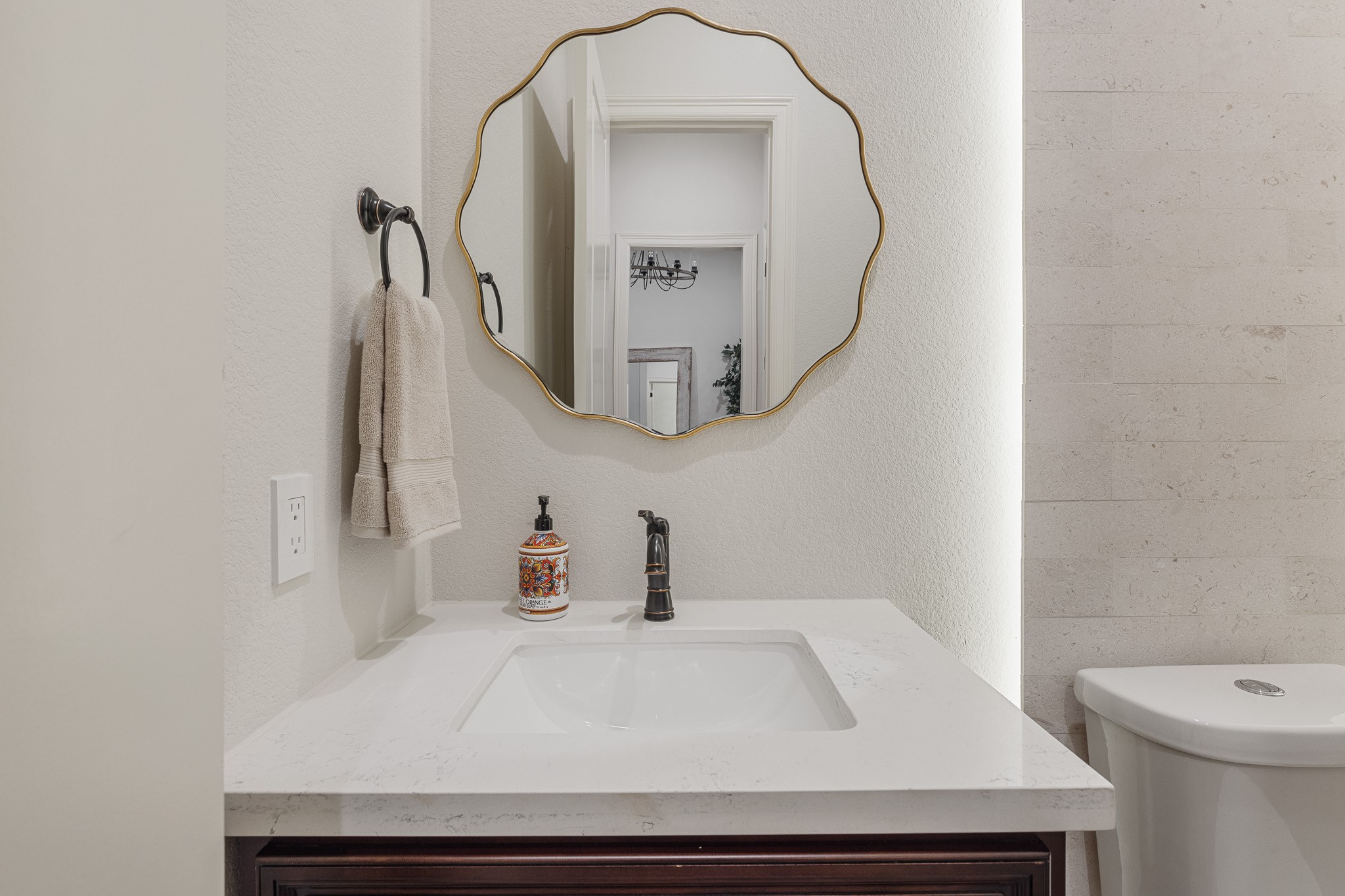 Half bath with brush nickel finishes. Back lit limestone wall.
