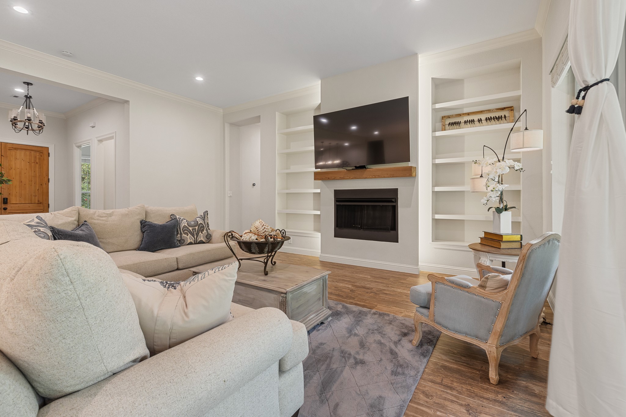 Living room with gas fireplace, recessed lighting, built-ins.