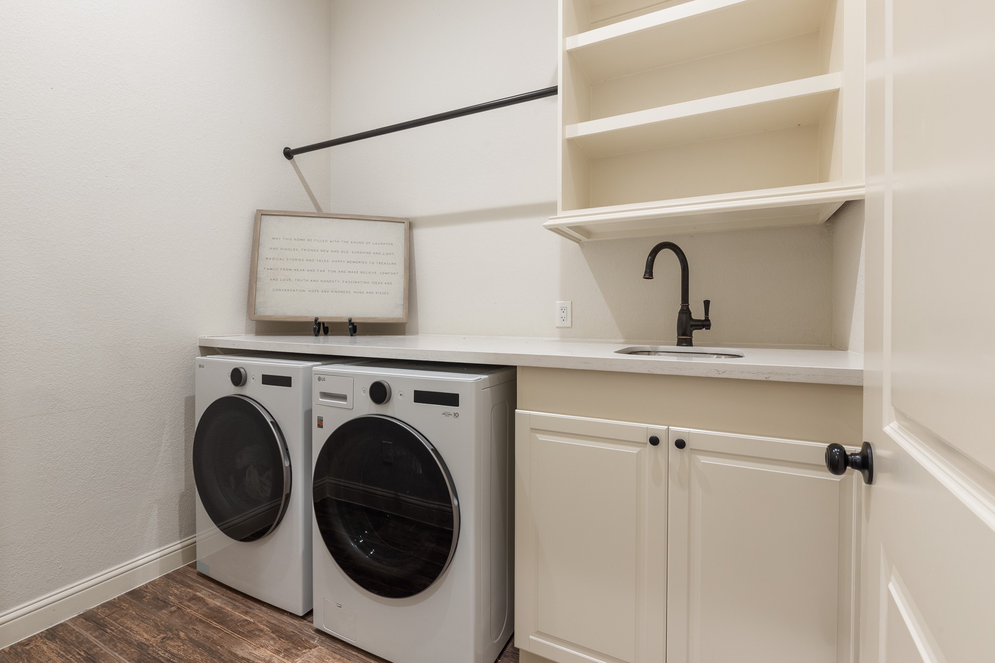 Laundry room with built-in shelving, utility sink.