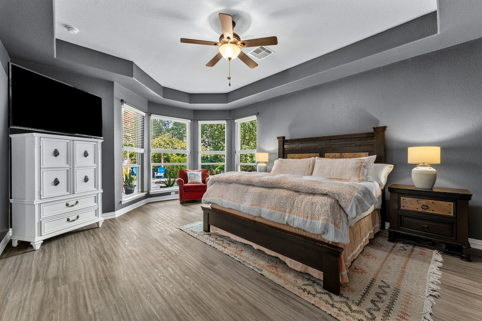 Your spacious primary suite is a true retreat offering a relaxing spot to unwind. Large bay windows let sunlight enter the room.