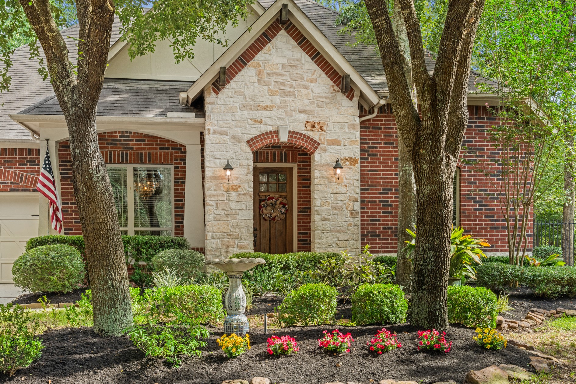 Curb appeal abounds with stone-lined flower beds and a stone and brick front elevation that also includes wood rafter accents and craftsman-style columns.