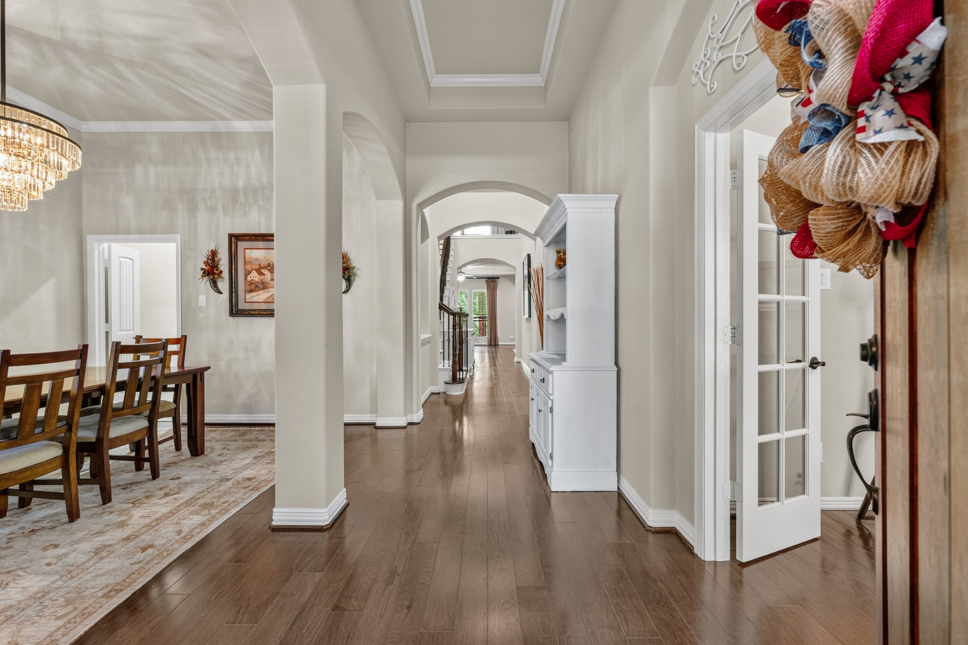 Inside, you'll find a warm, welcoming entry hall with high tray ceilings, arched openings, and gorgeious flooring.  The front entrance is flanked by the formal dining room on the left that connects to the kitchen and the home office on the right.
