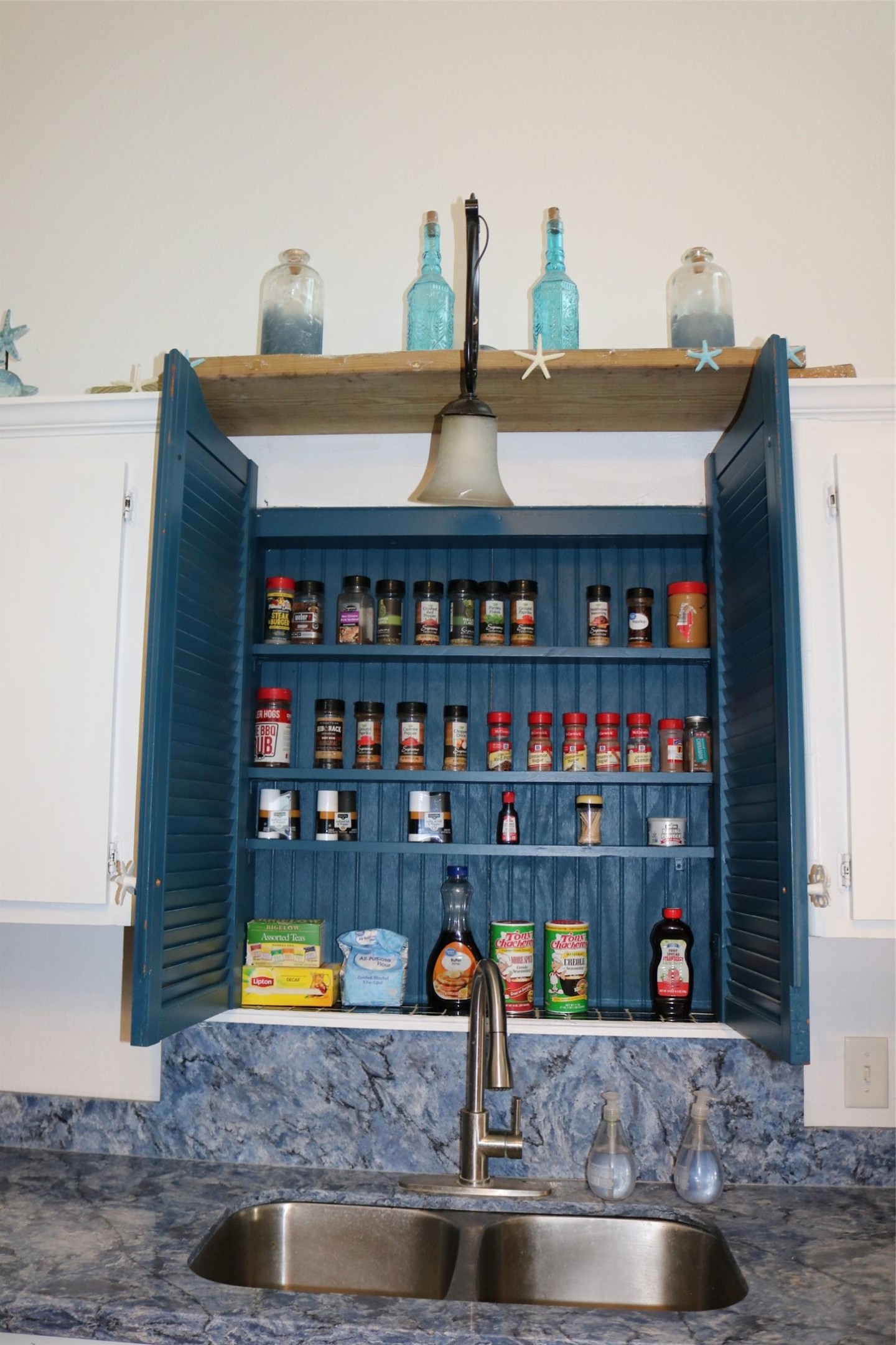 Conveniently located above the sink, this stylish spice rack adds both functionality and charm to the kitchen.