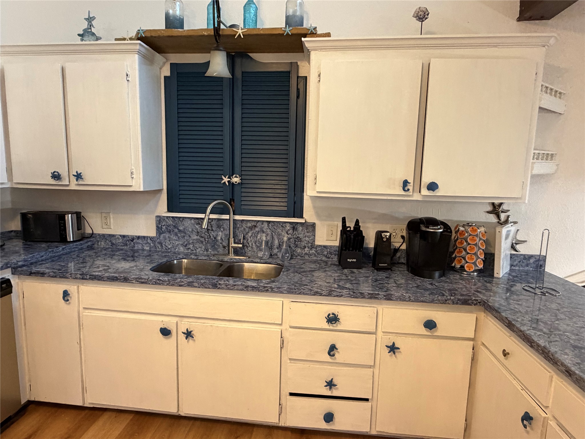 Charming kitchen with ample cabinetry, a convenient spice cabinet above the sink, and elegant countertops for a stylish and functional space.