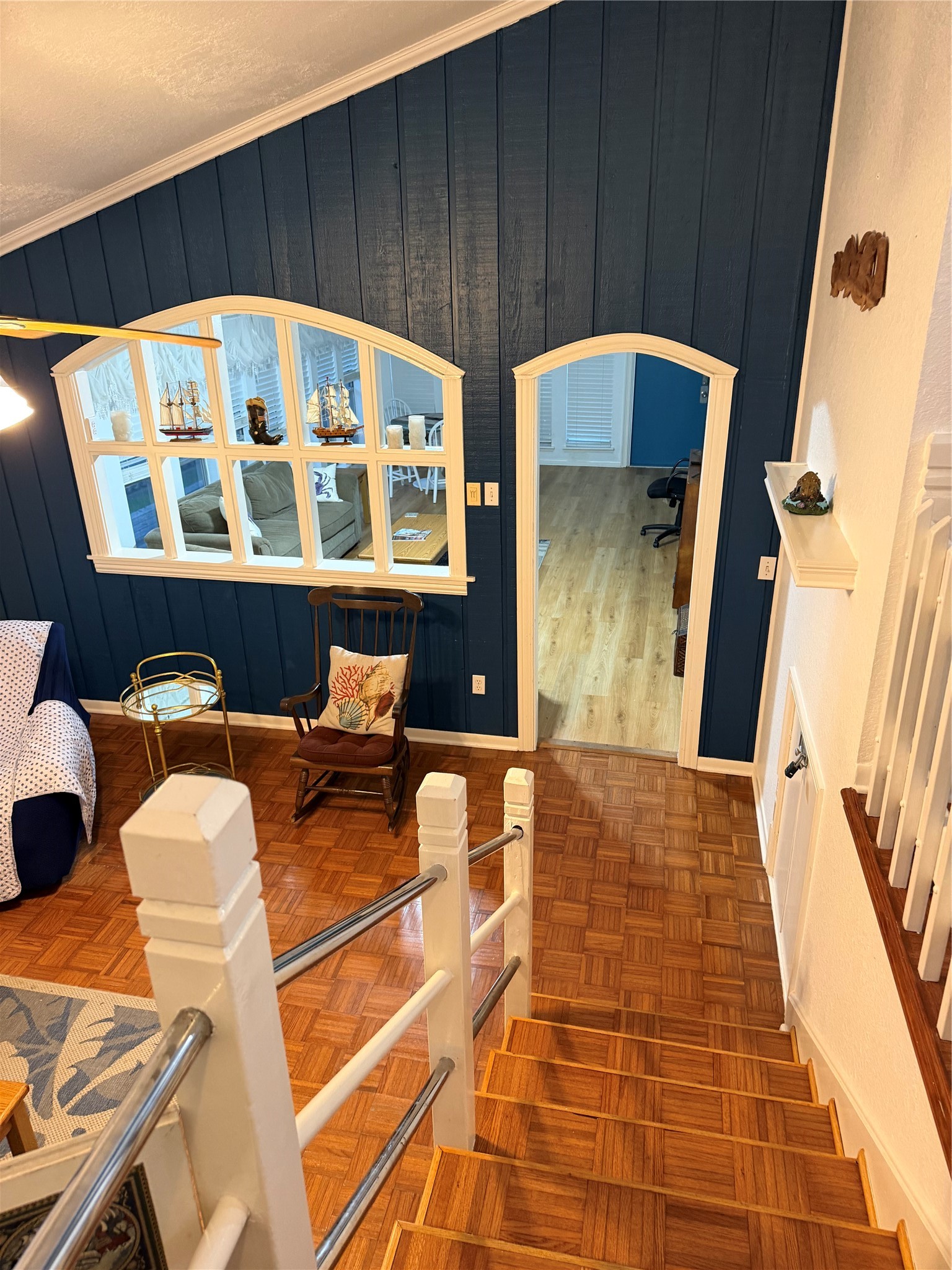 Descend into a cozy den/library featuring warm wood flooring and rich blue walls, perfect for relaxation and study.
