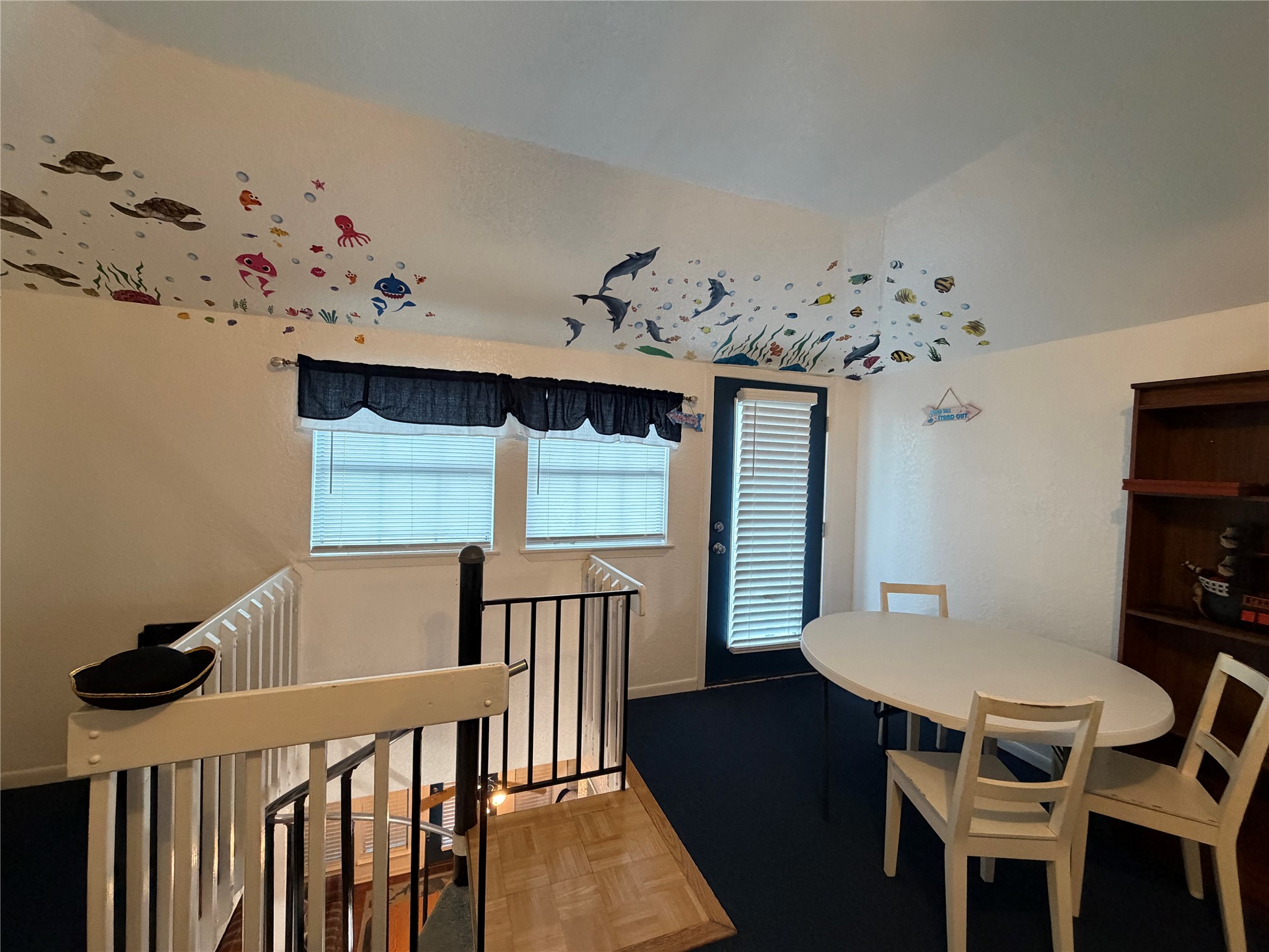 Dive into creativity in the third-level guest room, featuring captivating under-the-sea artwork on the ceiling, complemented by a cozy table and chairs.