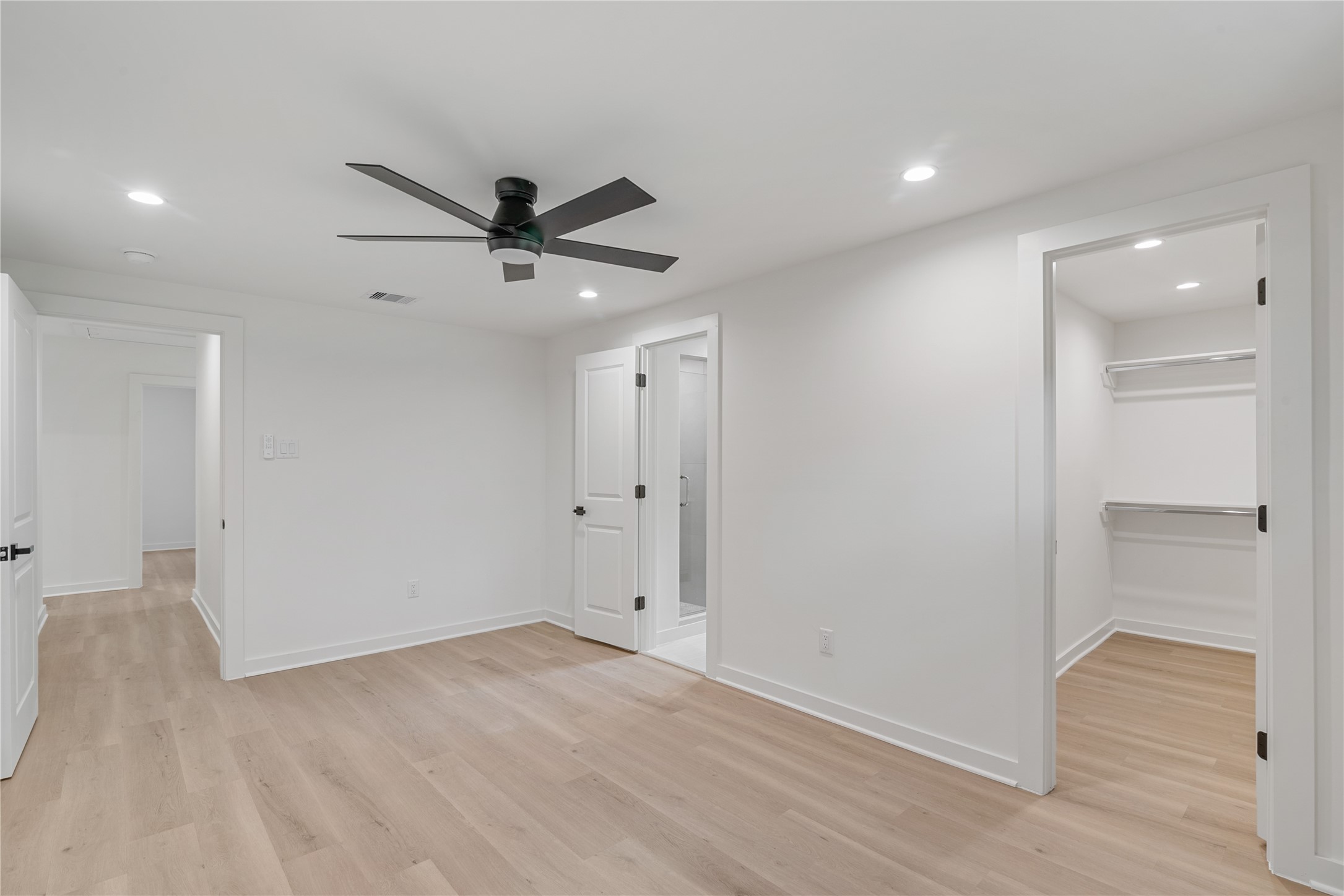 Additional bedroom view highlighting the generous floor space, ceiling fan, and access to adjoining rooms.