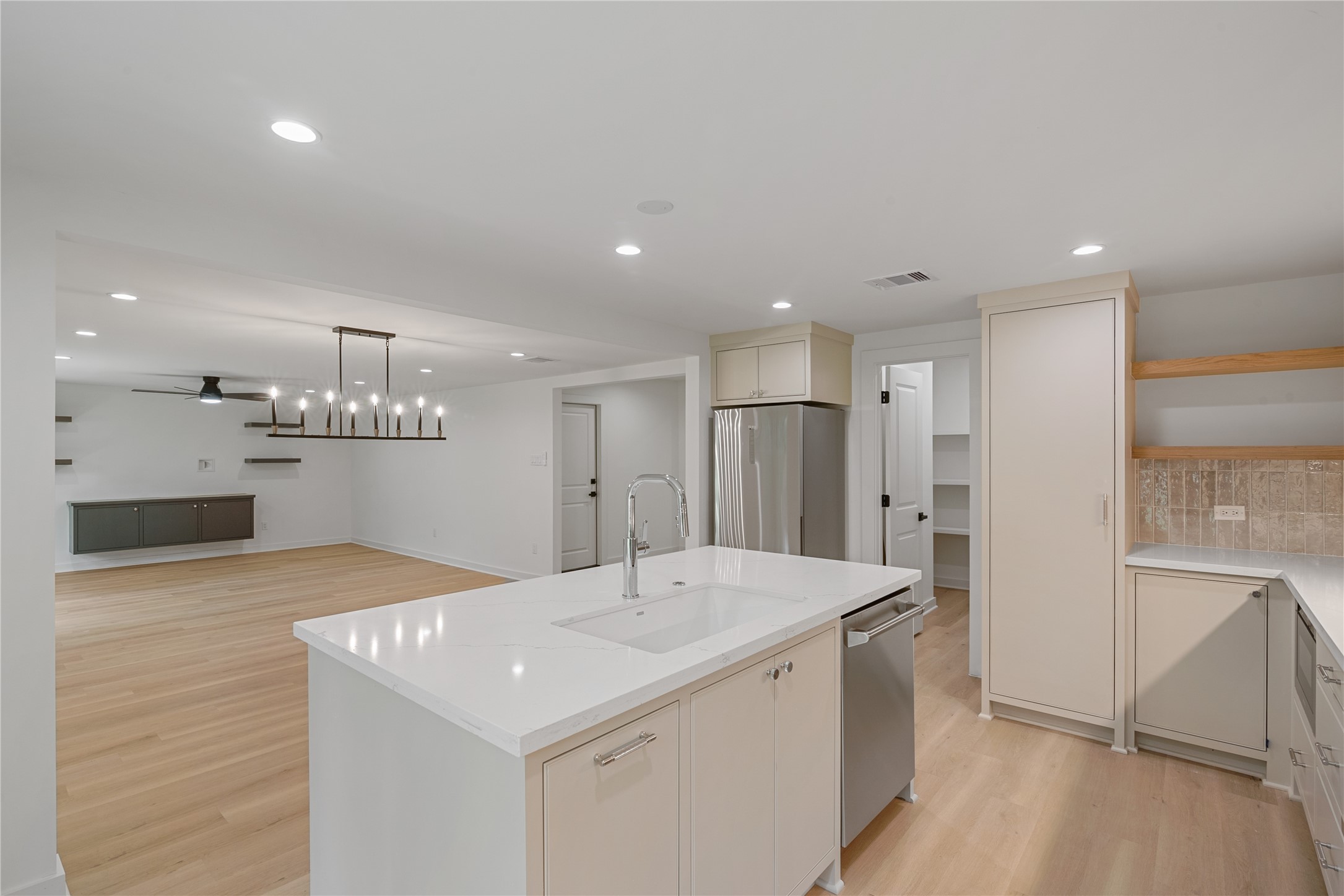 Wide-angle view of the remodeled kitchen featuring an expansive island, stainless steel appliances, and an open connection to the living area.