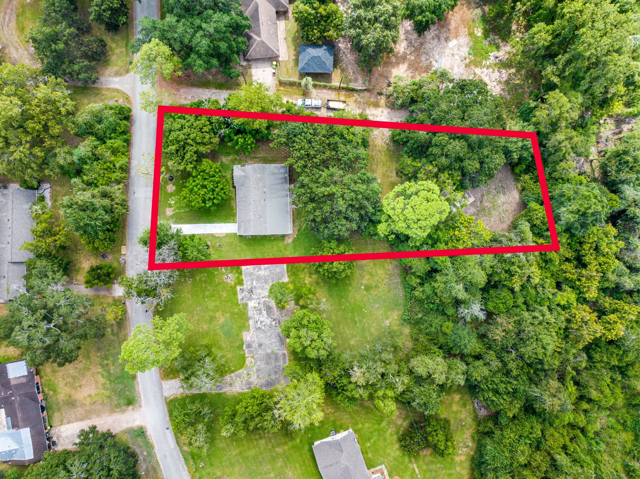 Top-down aerial view with approximate property boundaries outlined in red, illustrating the full scale and configuration of the nearly one-acre parcel.