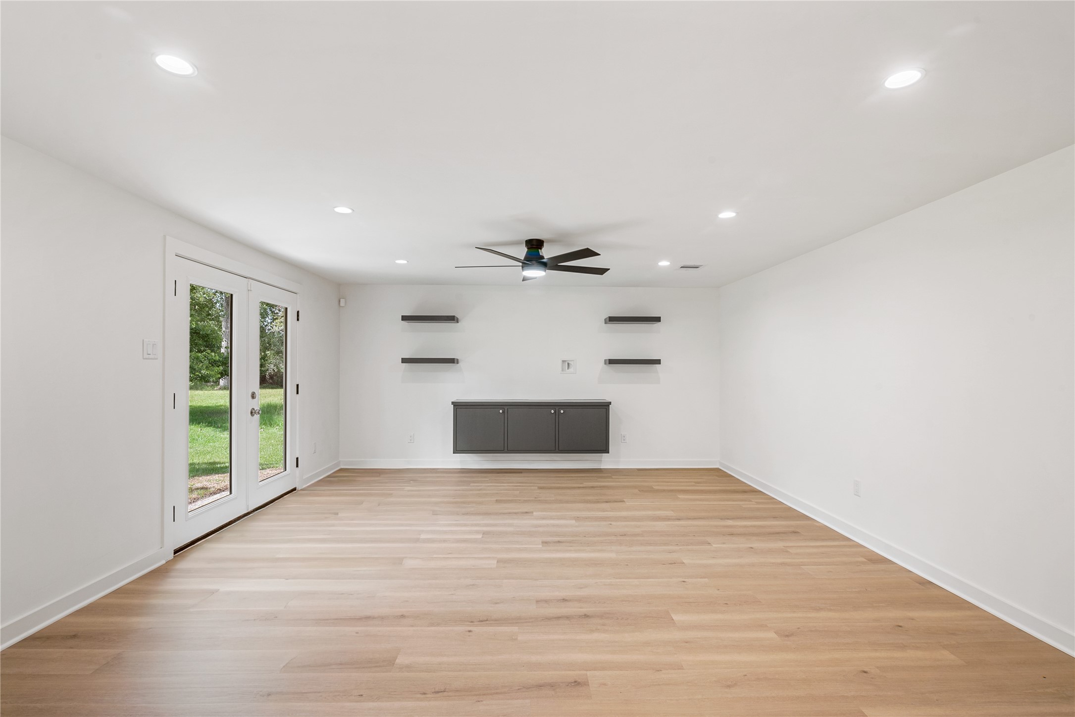 Generously sized living room features a contemporary ceiling fan, recessed lighting, and a sleek fireplace accent wall.