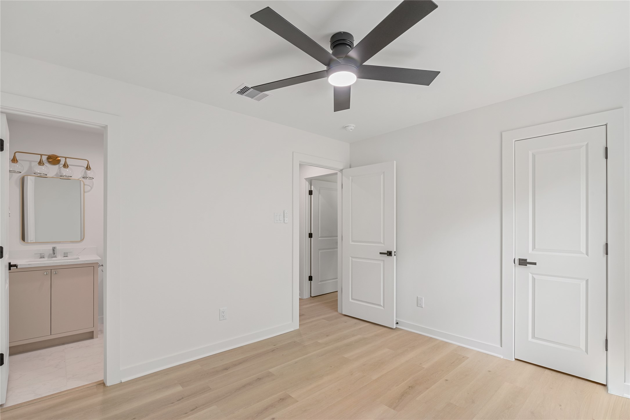 Another view of the bedroom showcasing the double-door closet, contemporary ceiling fan, and fresh neutral finishes.