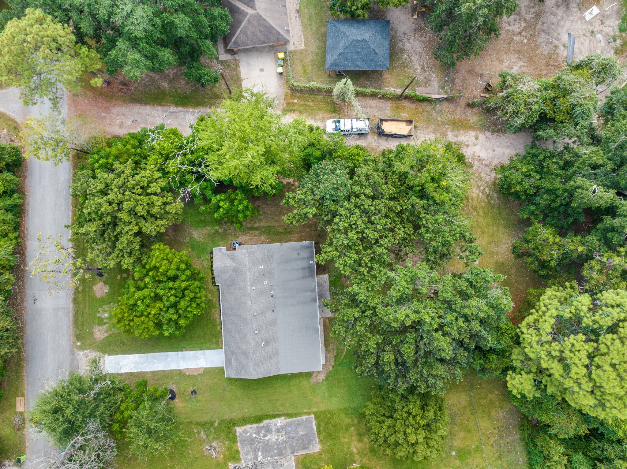 Straight-down aerial view showing the home's placement within the lot, surrounded by mature trees and expansive green space.