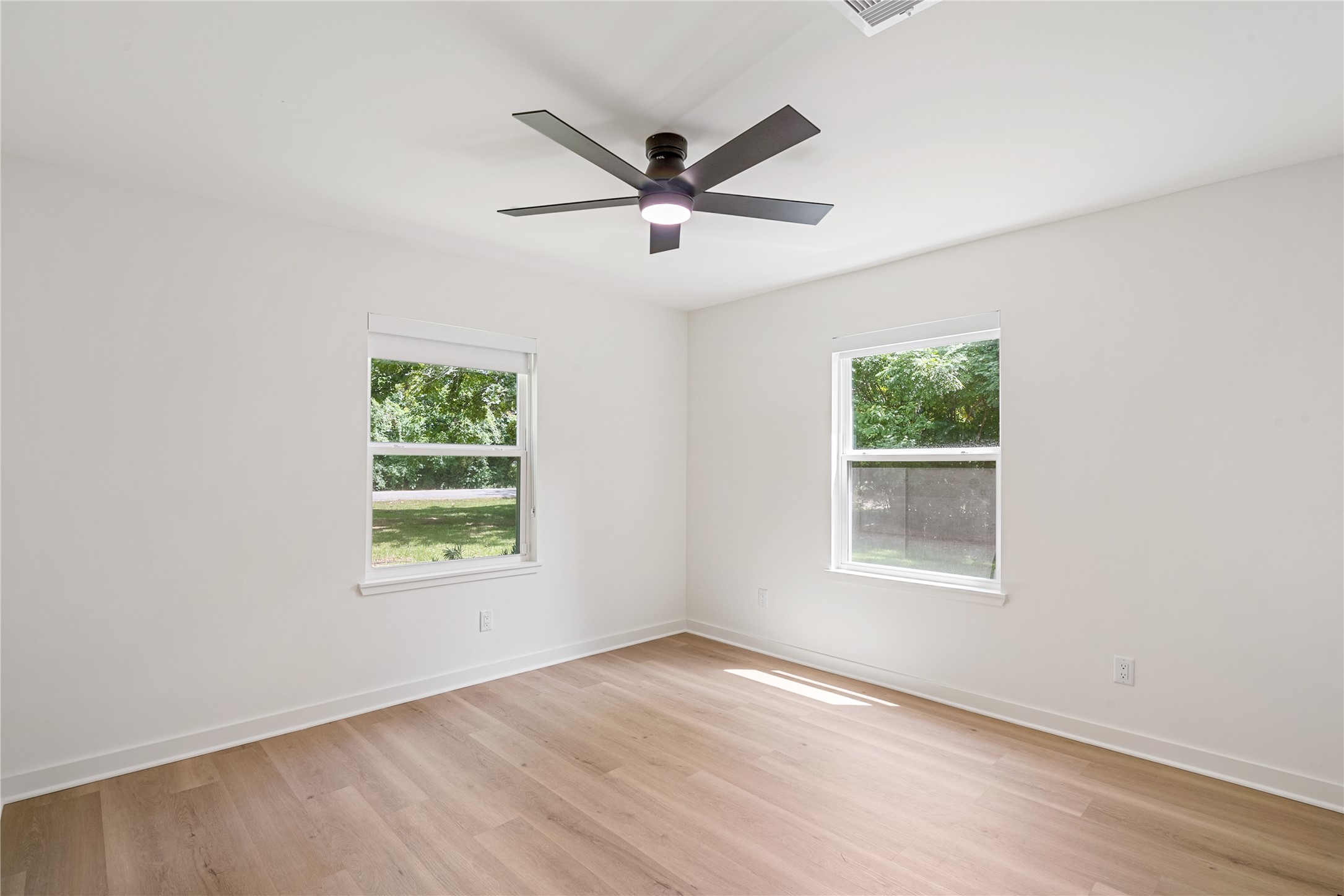 Bright bedroom featuring two windows, updated flooring, recessed lighting, and a contemporary ceiling fan.