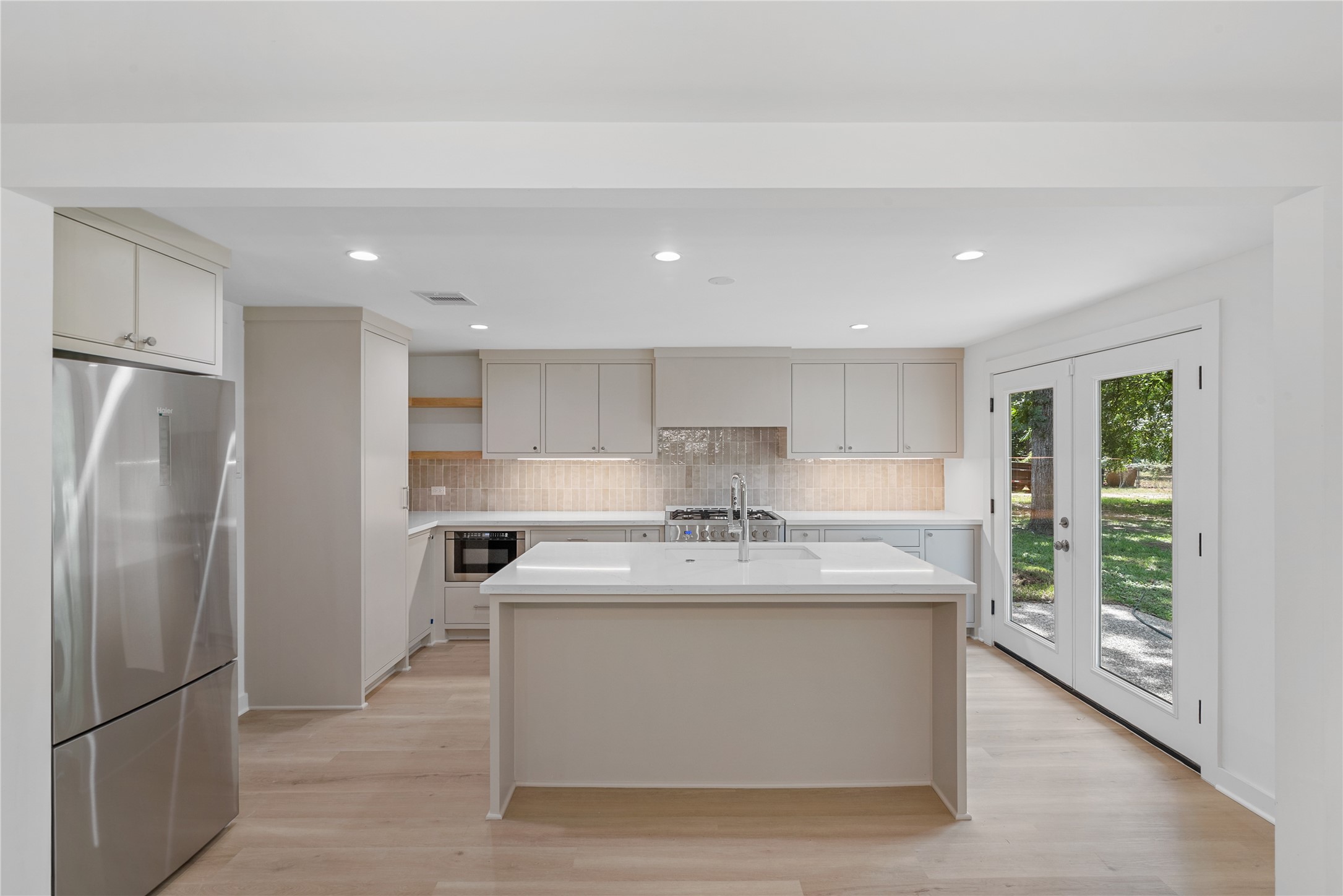 Beautifully updated kitchen featuring a large quartz-topped island, stainless steel appliances, custom cabinetry, and recessed lighting. Beautifully updated kitchen featuring a large quartz-topped island, stainless steel appliances, custom cabinetry, and recessed lighting.