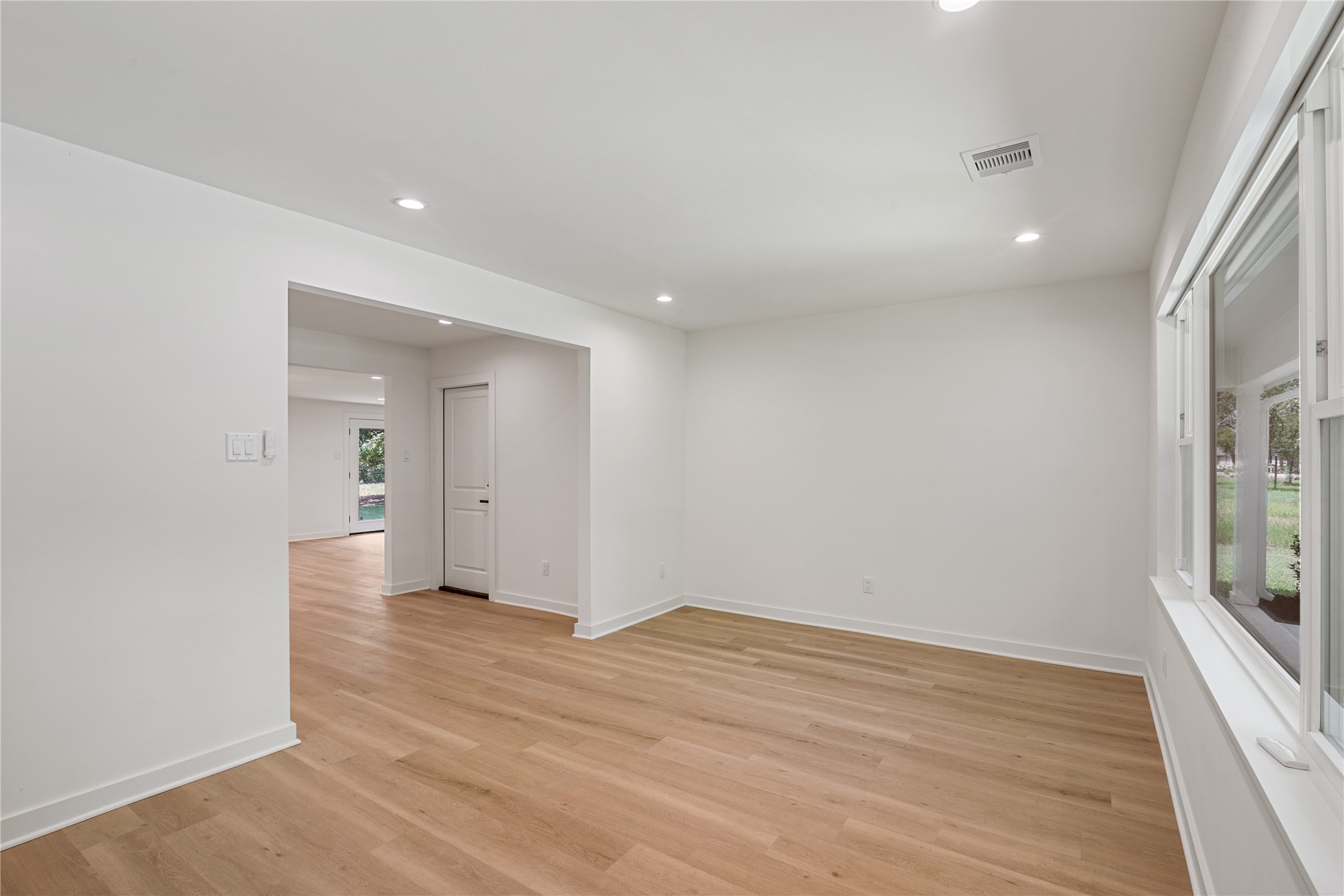Another view of the bright front living space, highlighting the open layout, neutral finishes, and connection to the rest of the home.