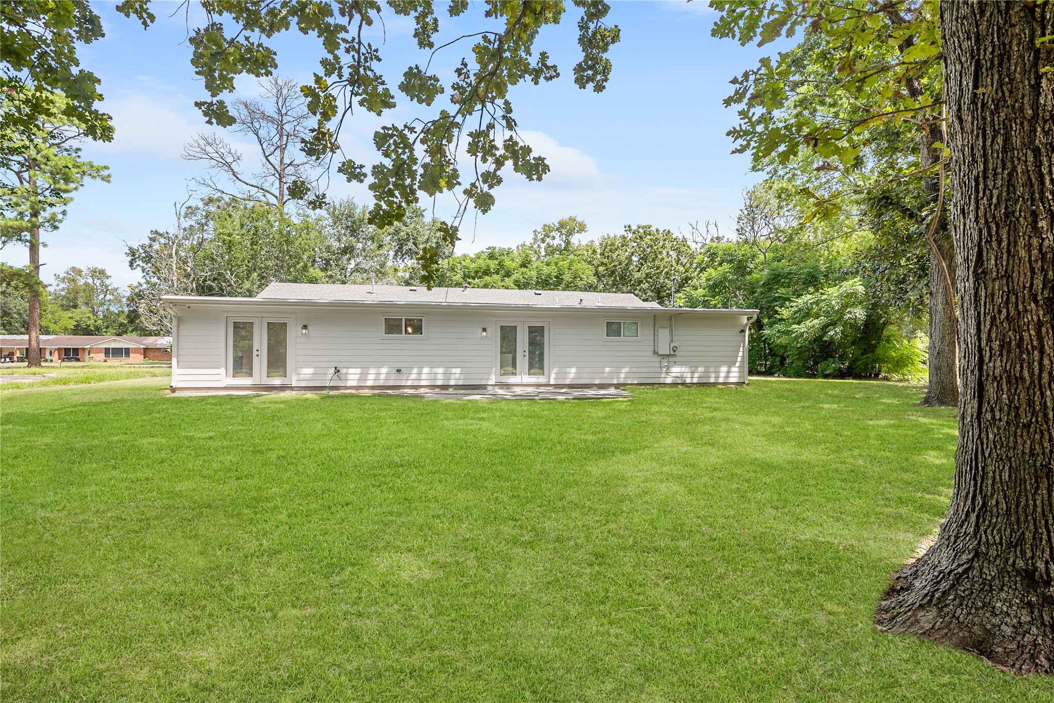 Expansive green lawn and mature shade trees create a beautiful setting around this renovated single-story home.