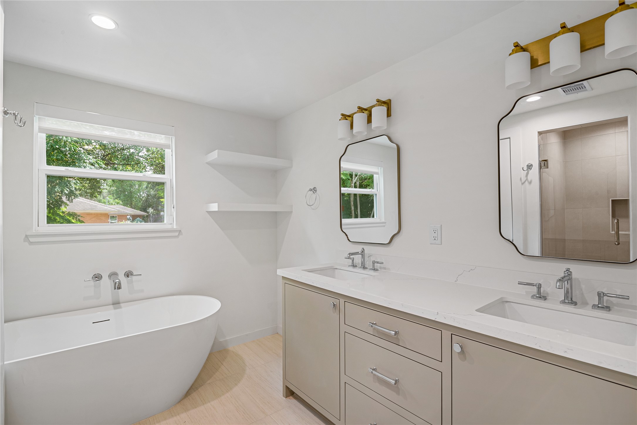 Beautifully renovated bathroom featuring a freestanding soaking tub, separate tiled shower, dual-sink vanity, and stylish modern fixtures.