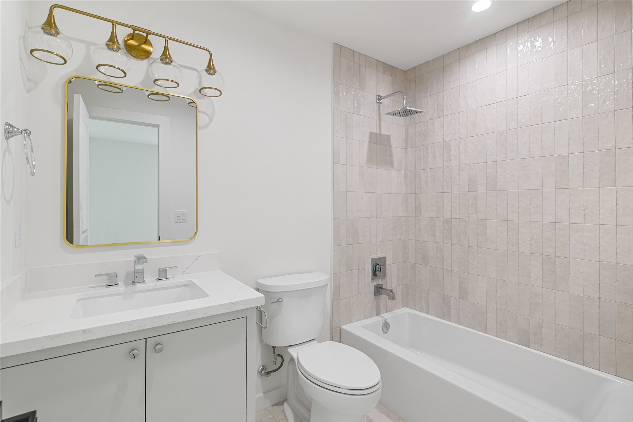 Updated full bathroom featuring a tub and shower combination with decorative tile surround, modern vanity, and coordinated fixtures.