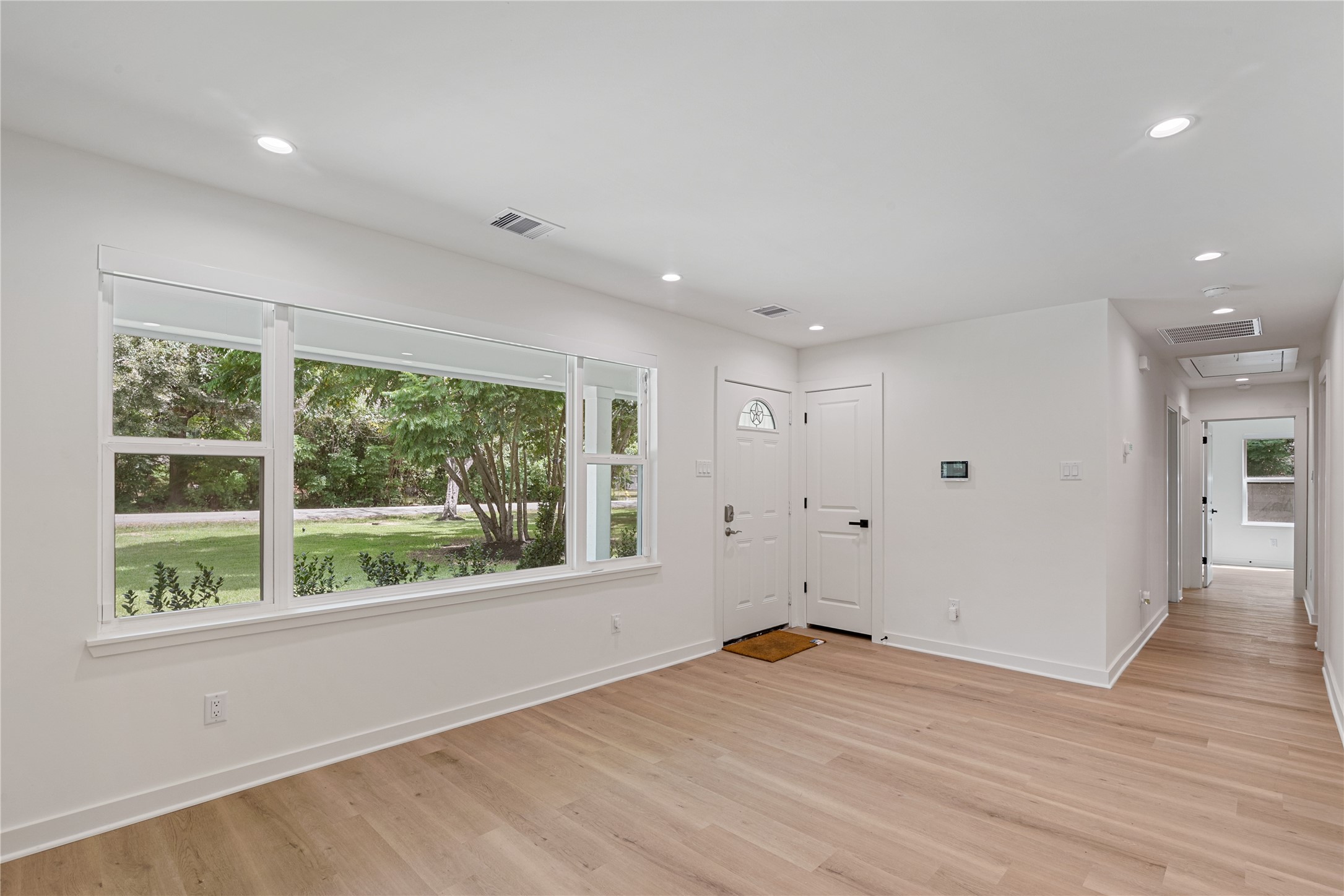 Large windows bring natural light into this versatile living space, complemented by updated flooring and fresh neutral finishes.