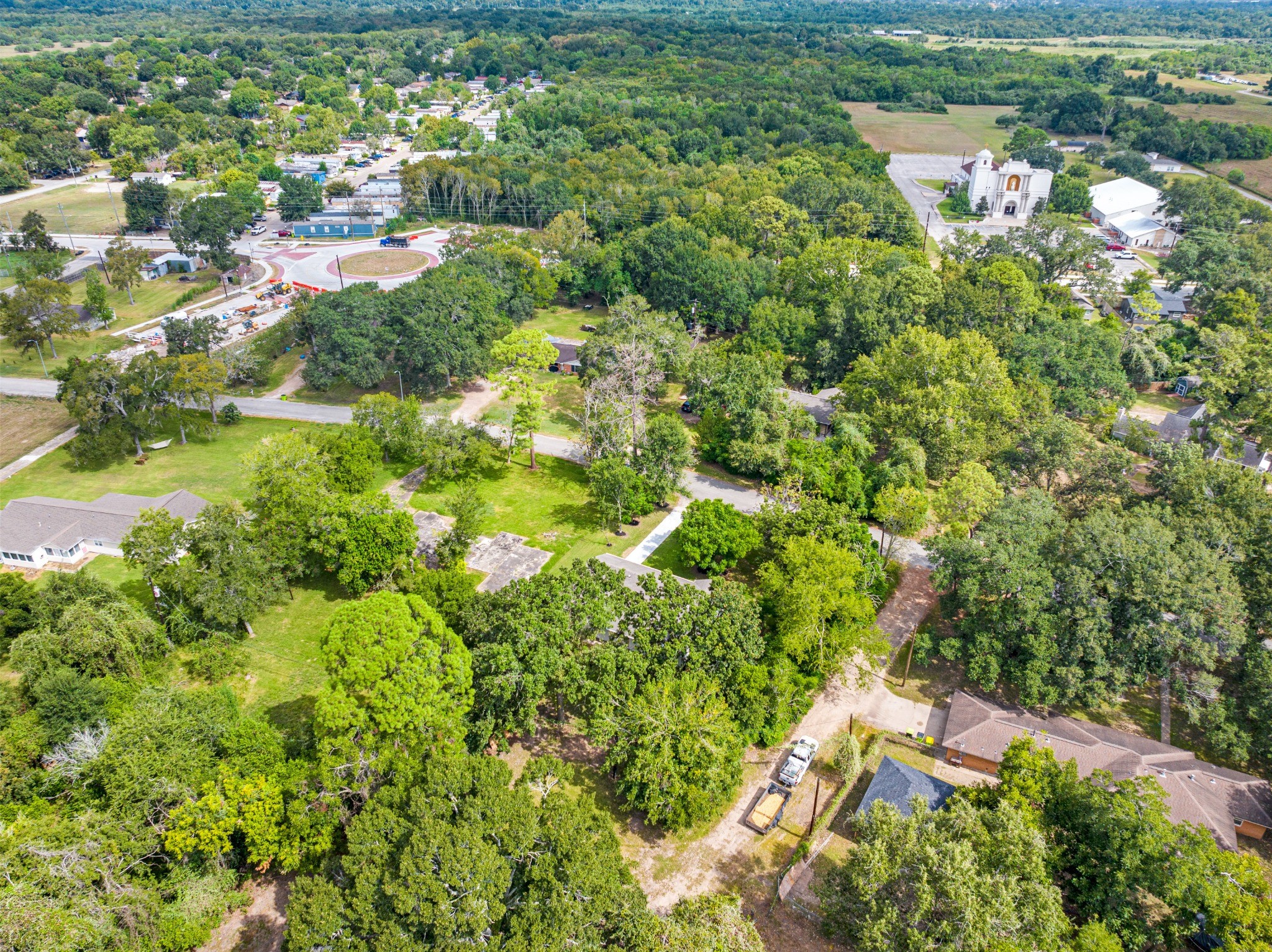 Wide aerial view highlighting the surrounding neighborhood, mature tree canopy, and spacious residential setting.