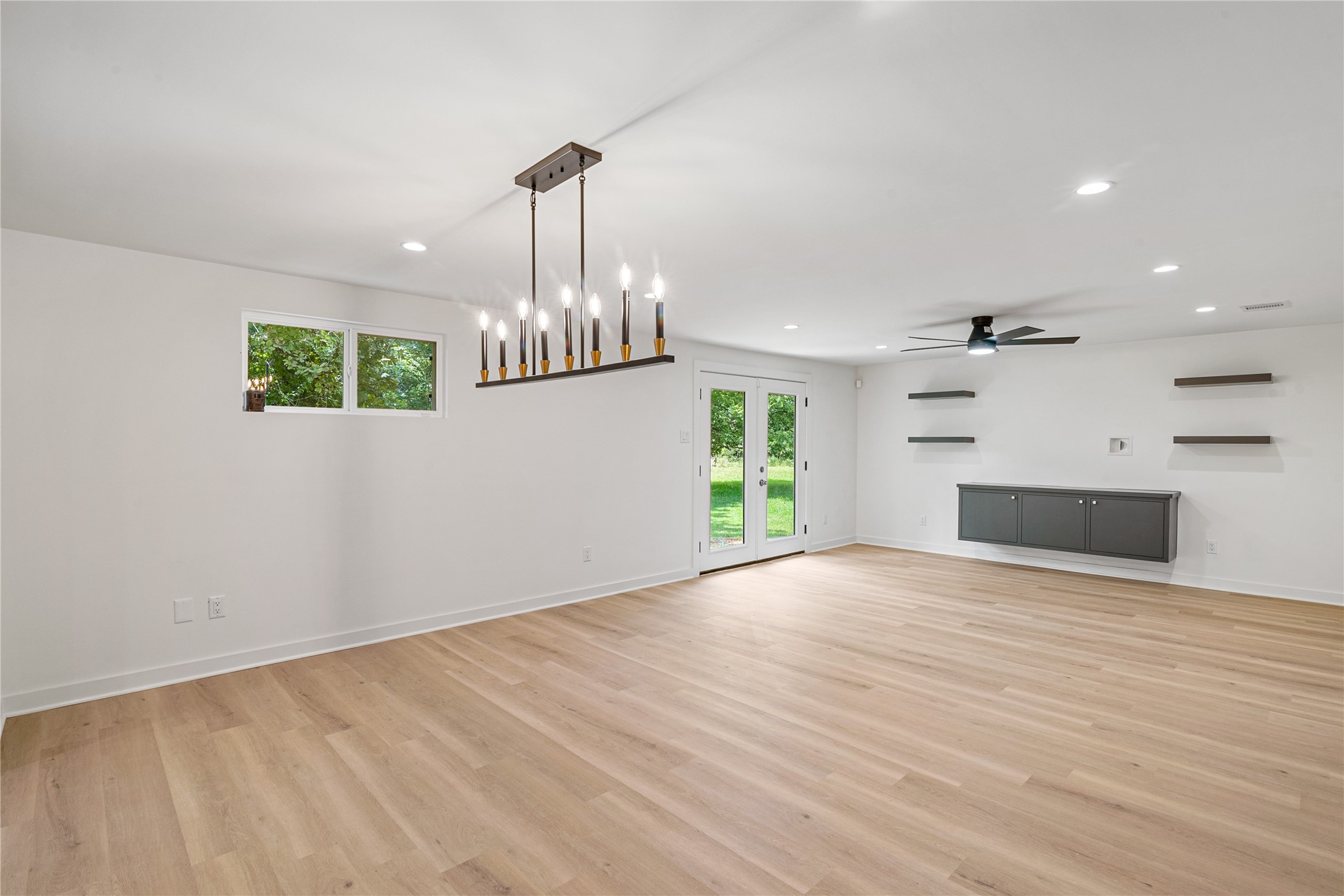 Bright, open living and dining areas feature updated flooring, recessed lighting, and a modern chandelier.