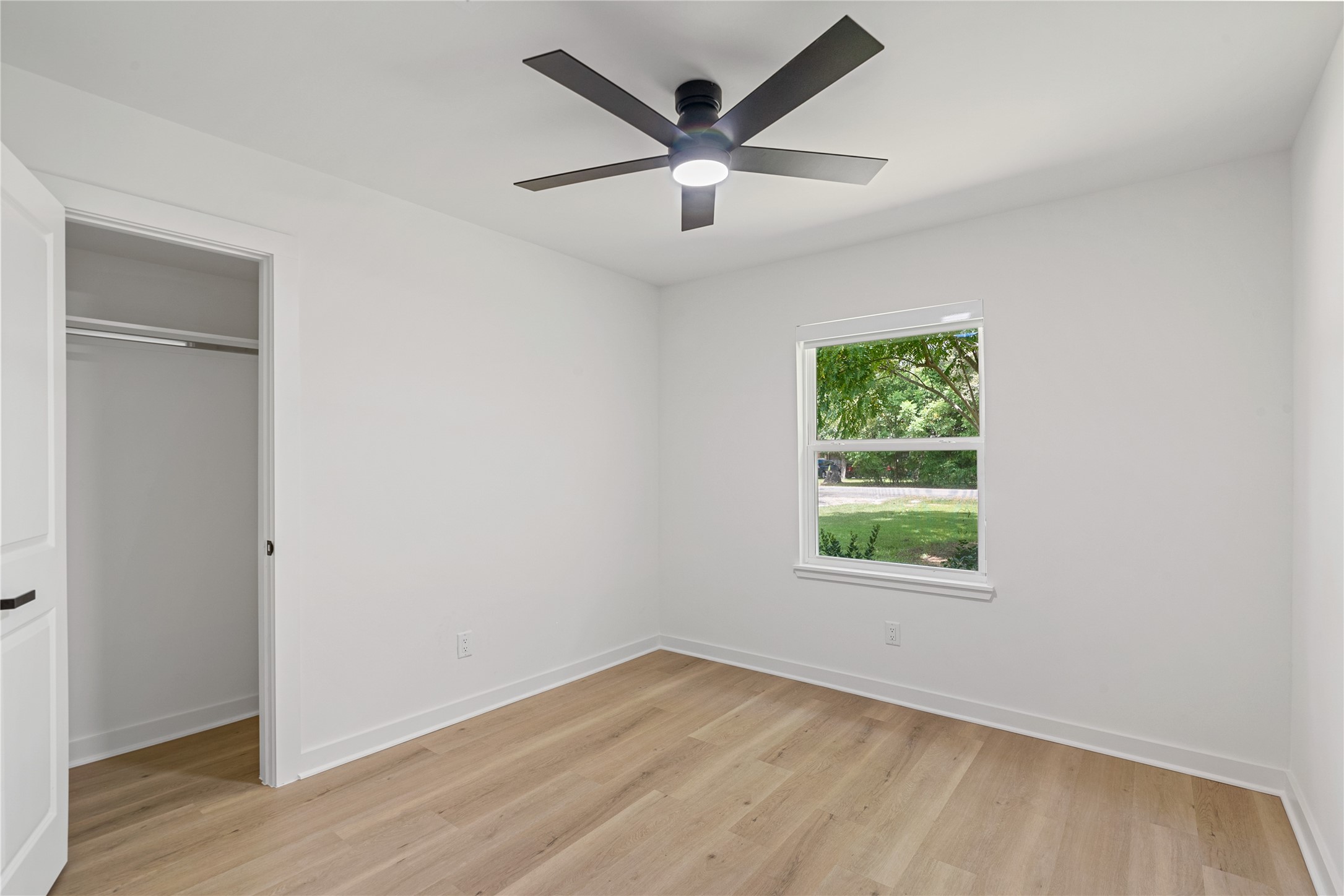 Bright secondary bedroom with updated flooring, a modern ceiling fan, and a window providing natural light.