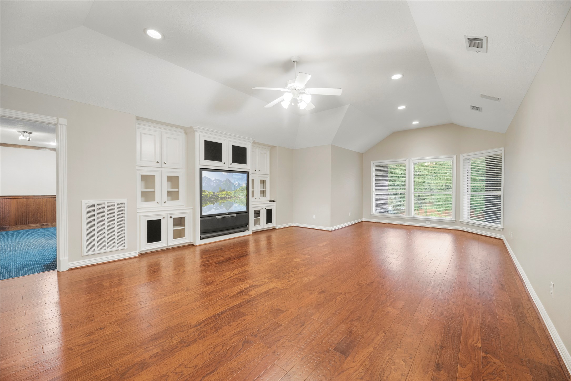 Versatile upstairs game room featuring rich hardwood flooring, vaulted ceilings and custom built-ins.
