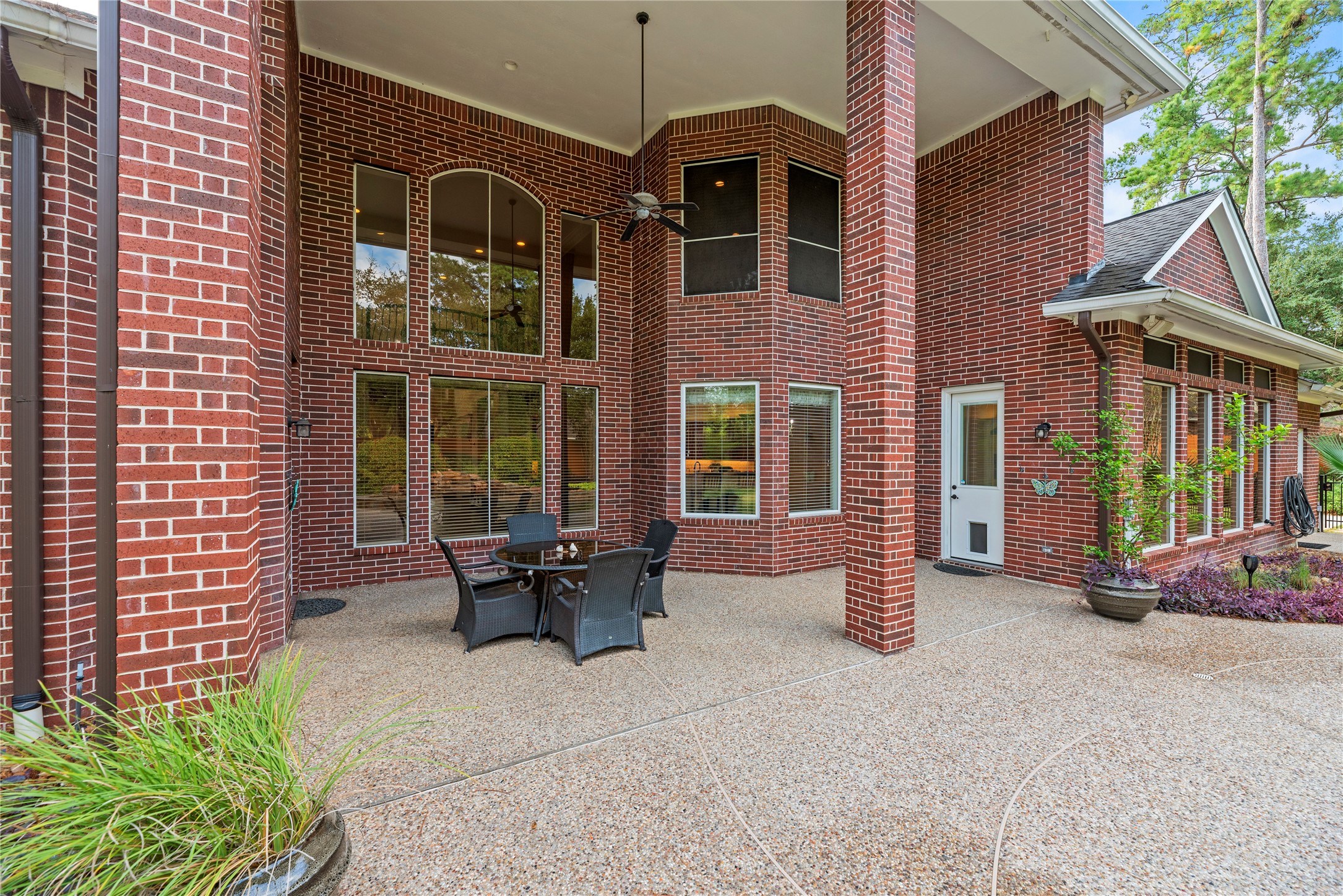 Expansive covered patio with soaring ceilings, stately brick columns, and an outdoor living area, offering a beautiful setting for al fresco dining and relaxation.