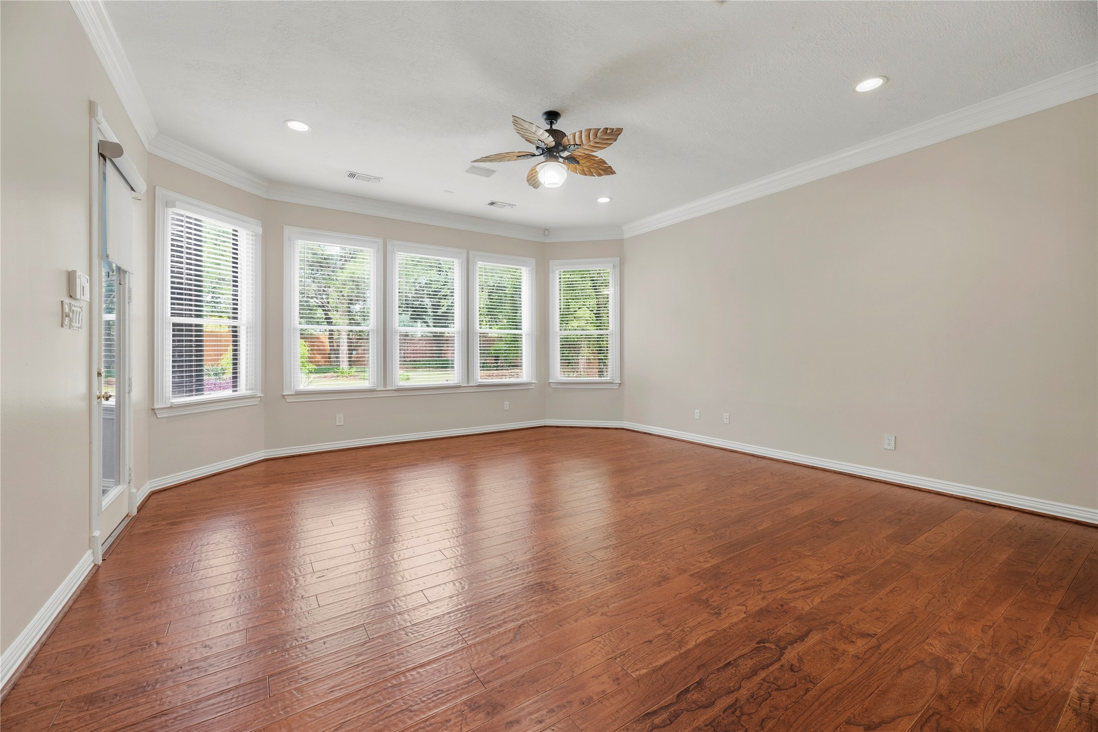 Primary retreat boasts wood flooring, crown molding, a sitting area, access to the backyard and an en-suite bathroom.