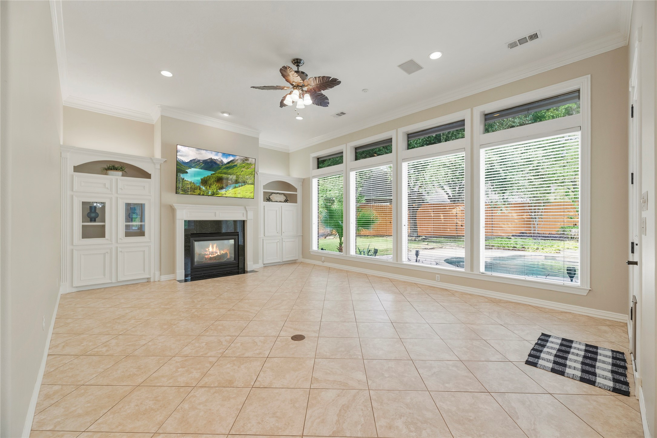 Family room offers tile flooring, a cozy fireplace surrounded by custom built-ins and a wall of windows with backyard views.