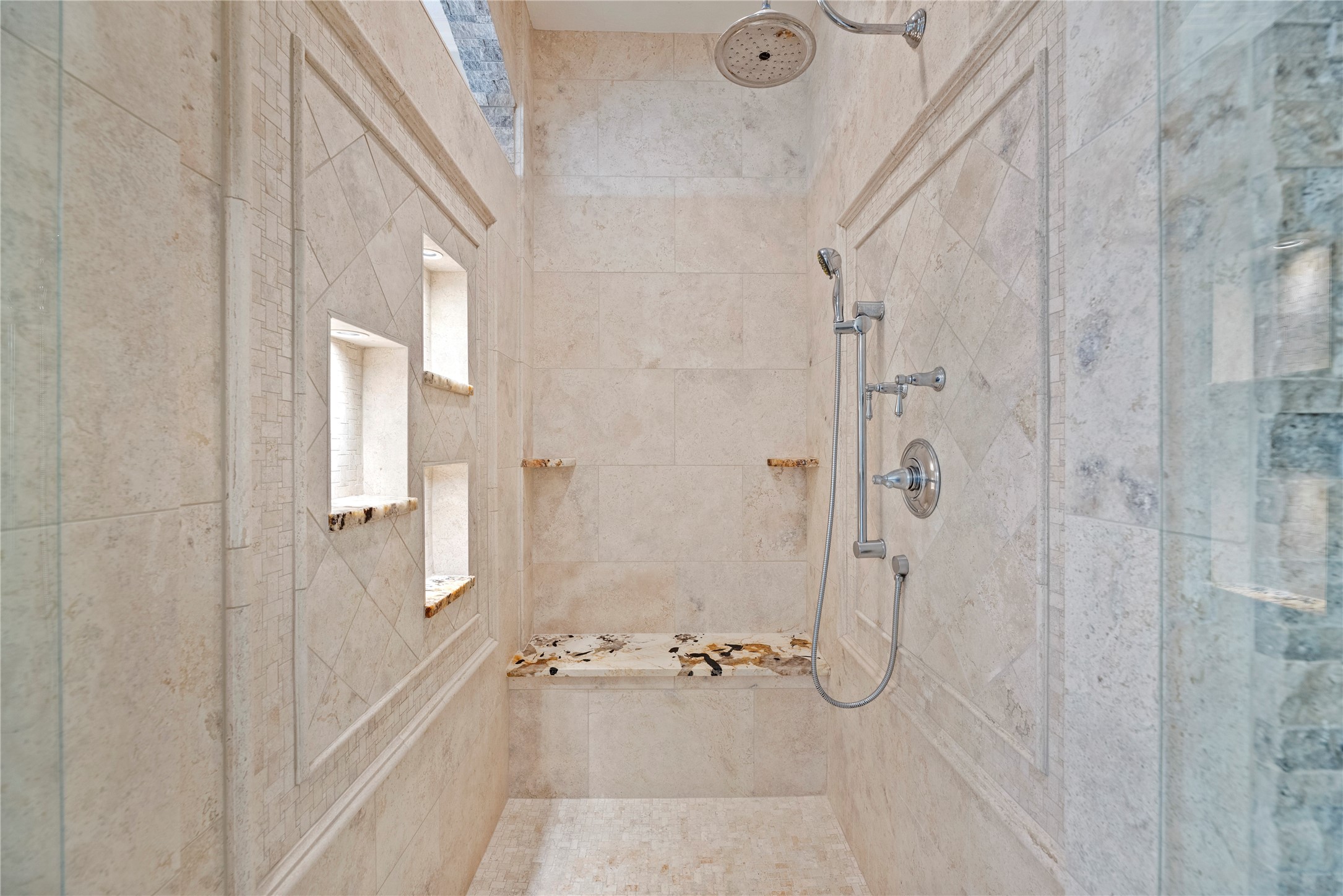Walk-in shower with lighted niches and a bench.