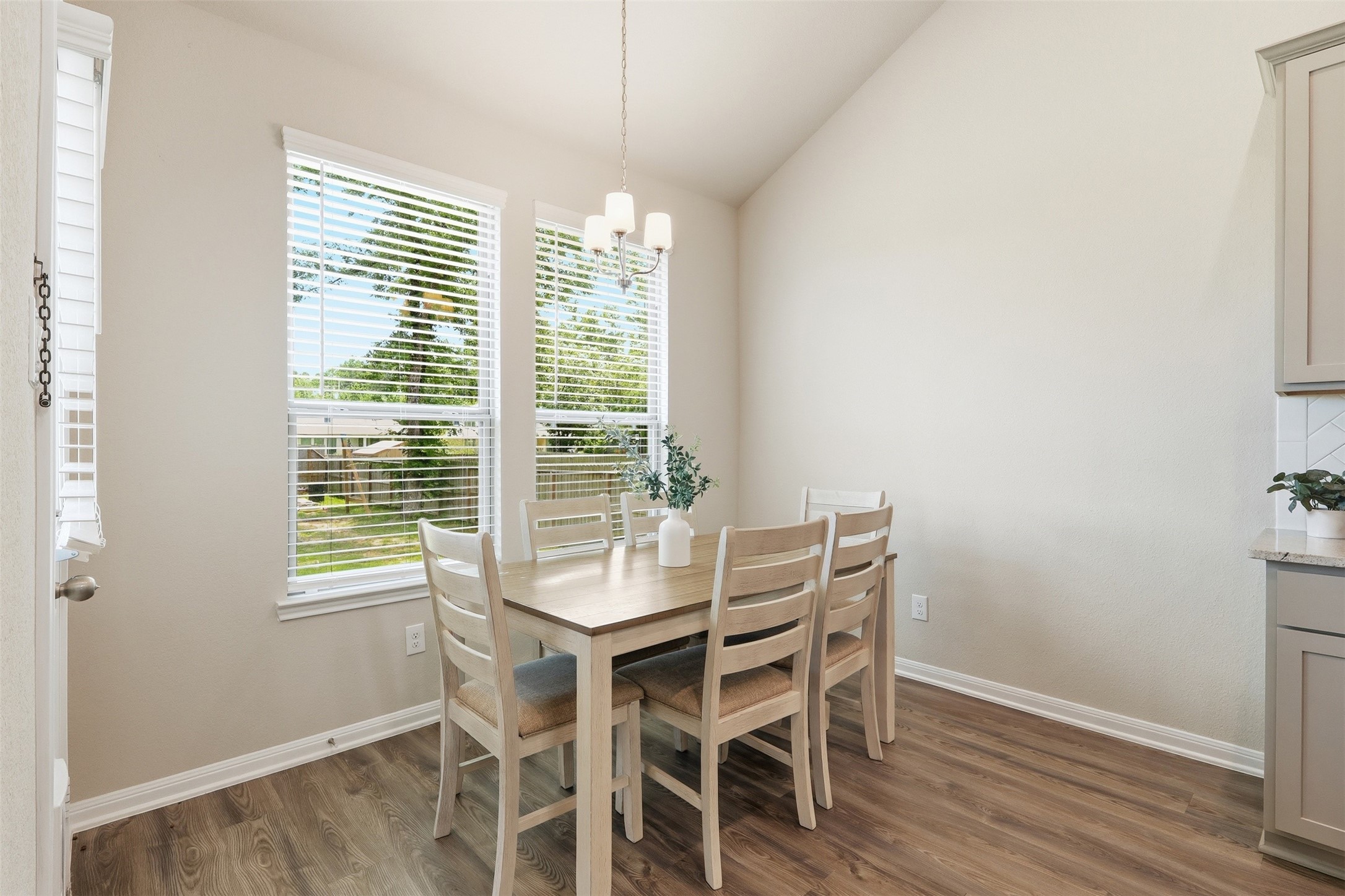 Bright dining area featuring large windows, beautiful backyard views, abundant natural light, and an open flow to the kitchen and living room.