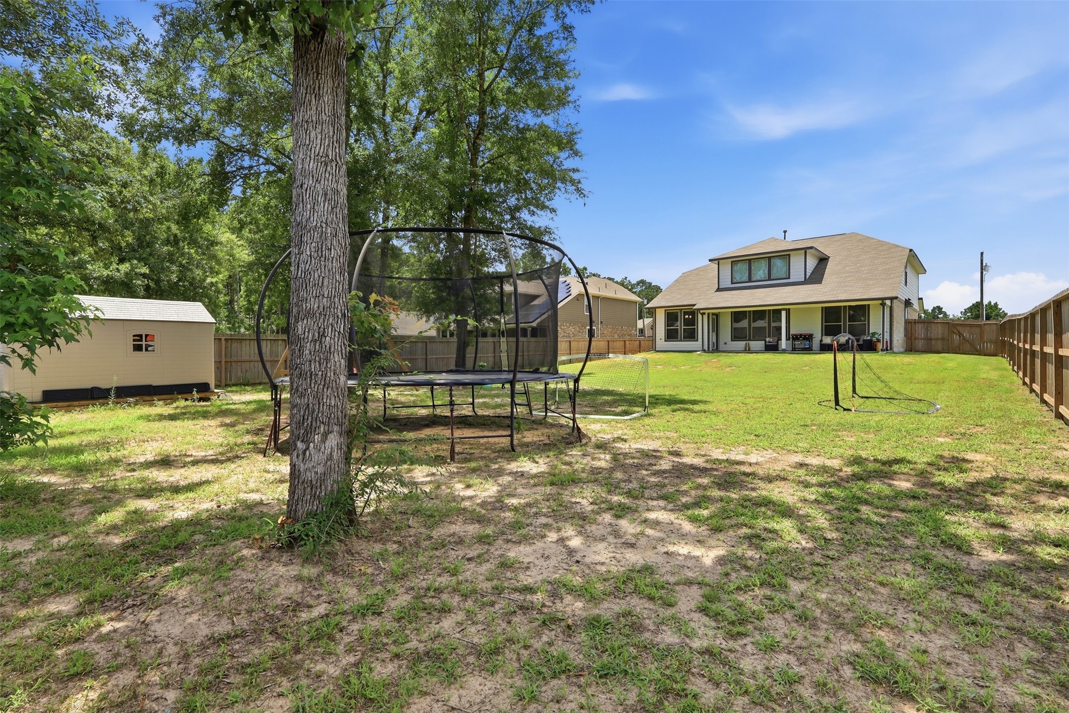Expansive fenced backyard featuring a covered patio, storage shed, and playset, which come with the home. Plenty of space to entertain, play, and enjoy outdoor living.
