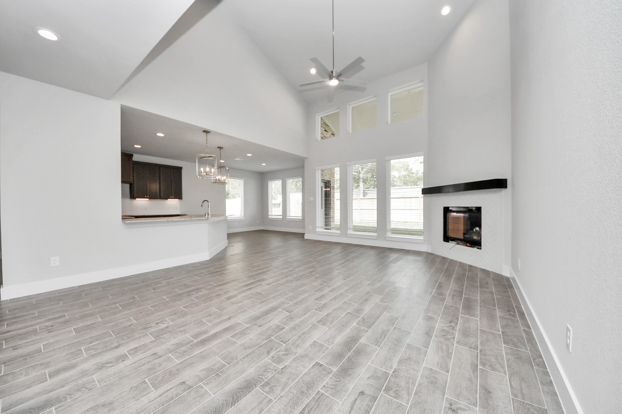 Family room flooded with natural light through the expansive windows.  The premium tile flooring adds a touch of luxury to the space, creating the perfect setting for relaxing moments and cherished gatherings with loved ones. Sample photo of completed home with similar floor plan. Actual colors and selections may vary.