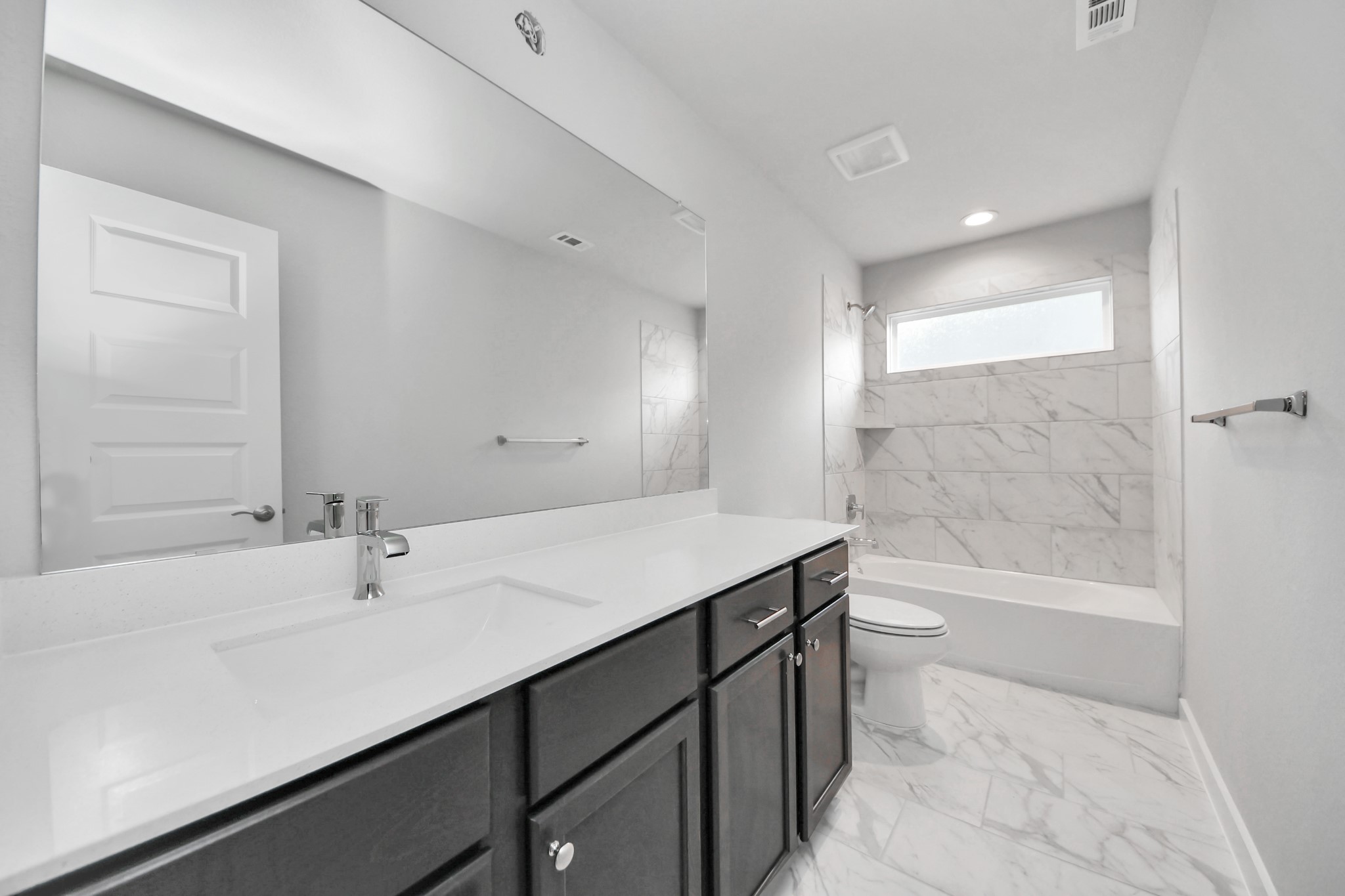 Secondary bath features tile flooring, bath/shower combo with tile surround, light stained wood cabinets, beautiful light countertop. Sample photo of completed home with similar floor plan. Actual colors and selections may vary.