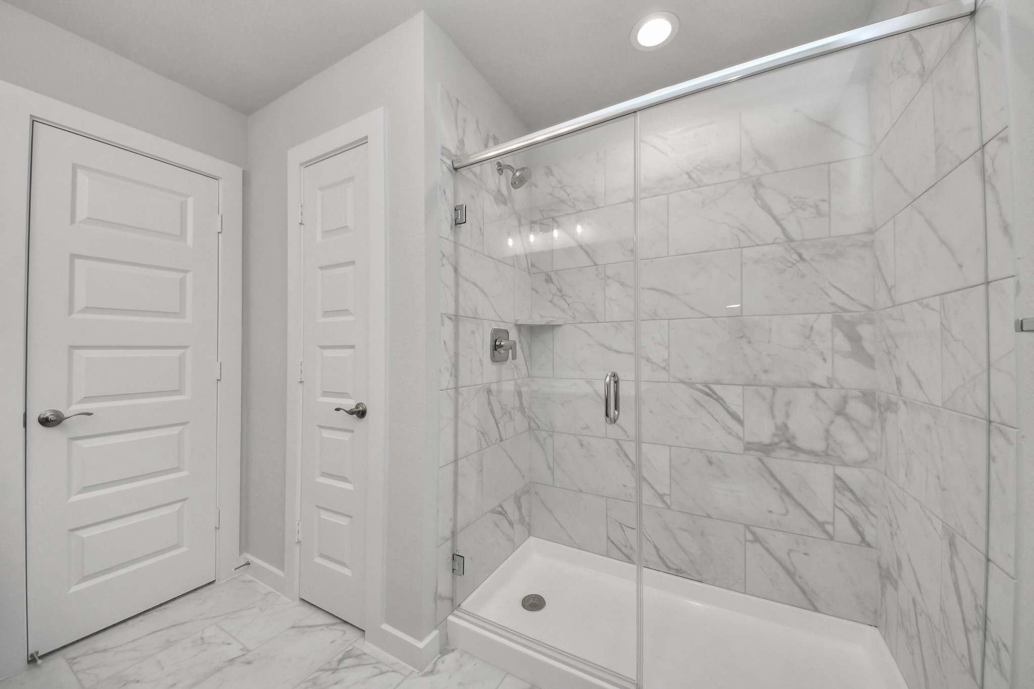Secondary bath features tile flooring, walk-in shower with tile surround, light stained wood cabinets, beautiful light countertop. Sample photo of completed home with similar floor plan. Actual colors and selections may vary.