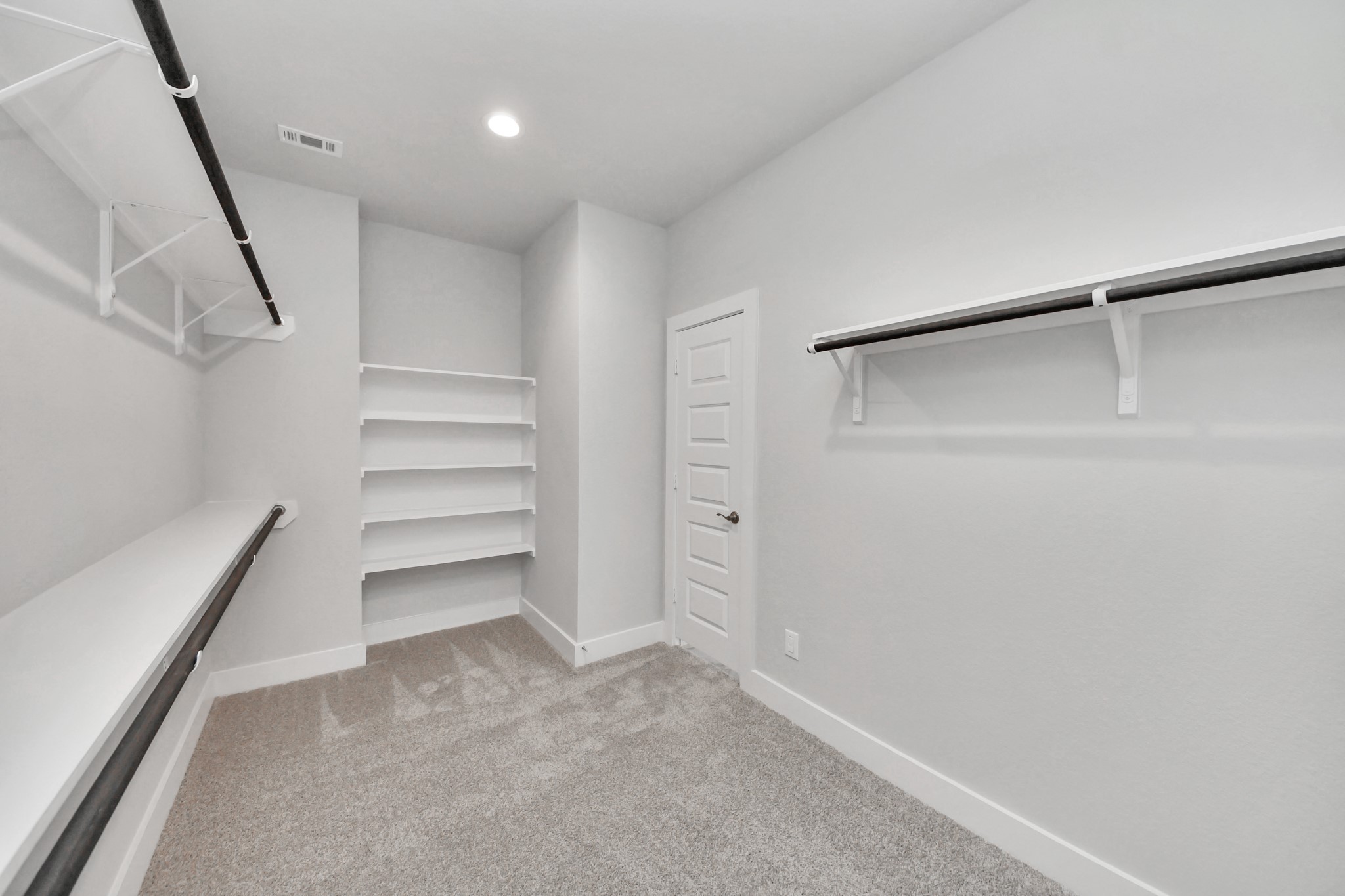 Walk-in closet that epitomizes luxury and practicality. This generously sized space features built-in shelving, offering abundant room for impeccable organization. High ceilings and recessed lighting create a bright and welcoming ambiance. Sample photo of completed home with similar floor plan. Actual colors and selections may vary.