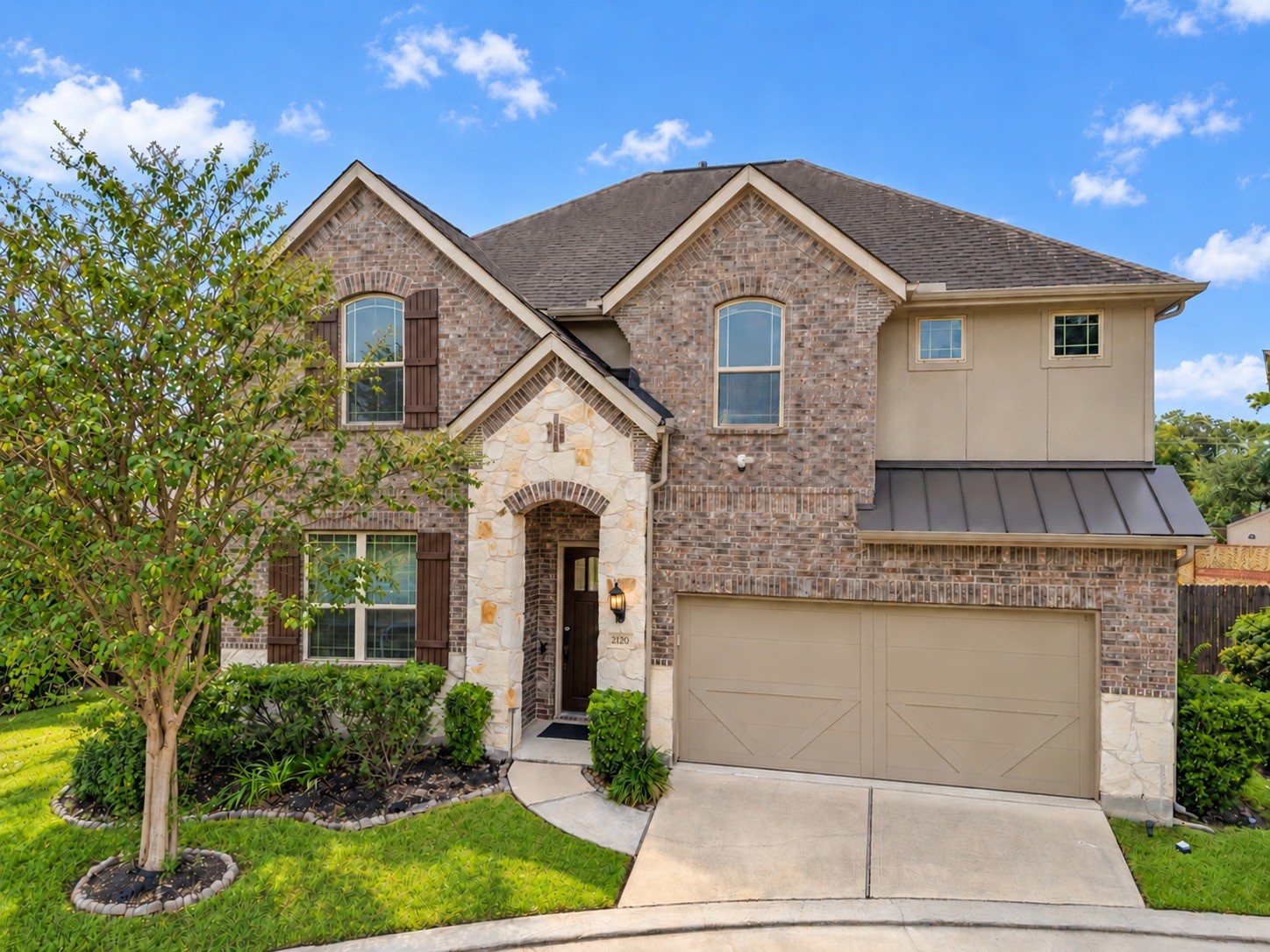 Beautiful brick and stone accents, distinctive rooflines, and an arched covered entry create inviting curb appeal. Landscaped garden beds and a two-car garage complete the homes welcoming exterior.