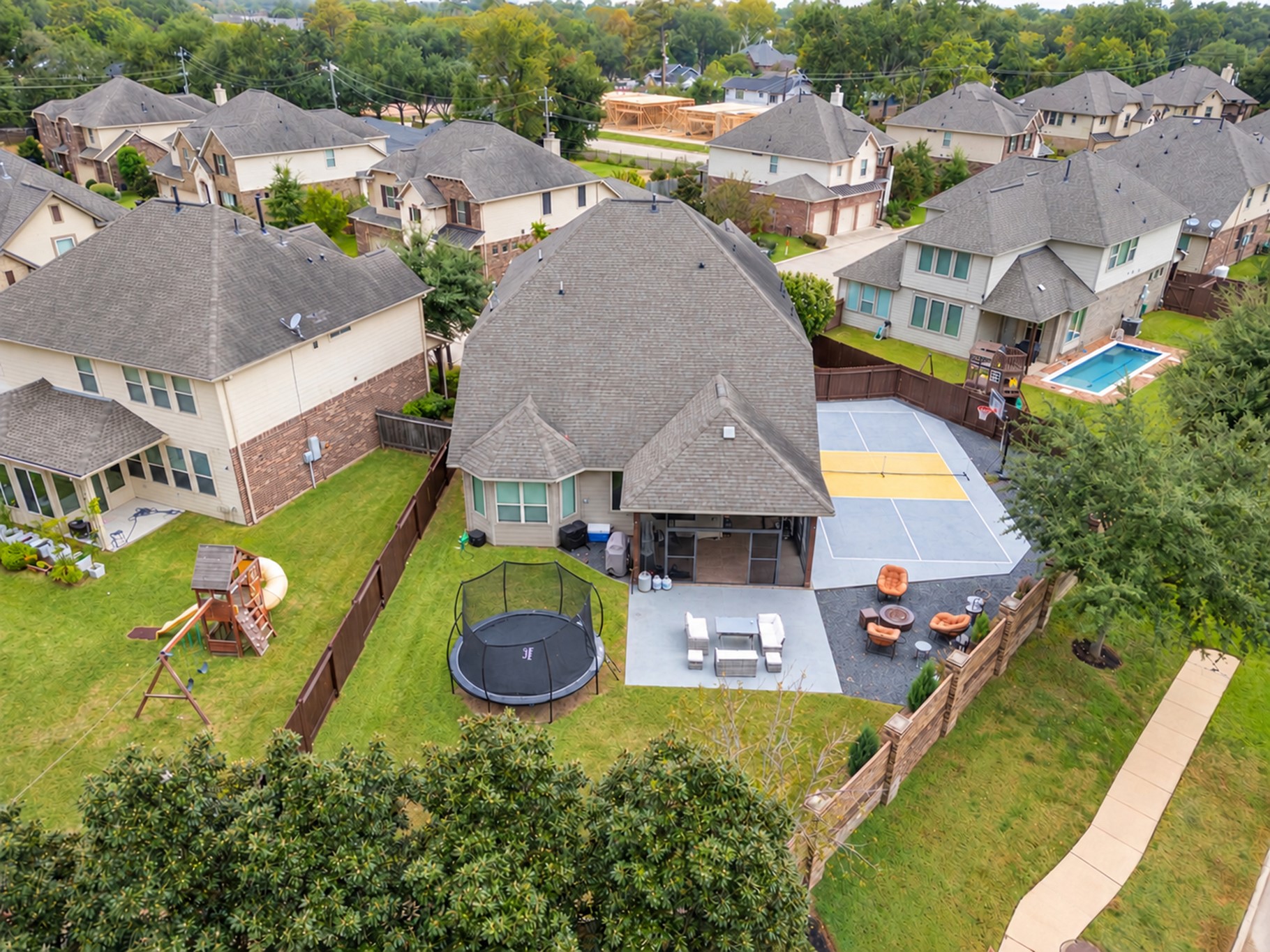 Enjoy your own private recreation retreat in this spacious backyard, featuring a screened-in covered patio, a multipurpose pickleball or basketball court, an expanded patio, and plenty of green space for outdoor fun and entertaining!