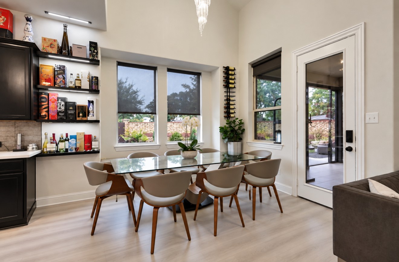 Light-filled dining area featuring high ceilings, updated flooring, and large windows overlooking the backyard. Conveniently located beside the kitchen with direct access to the screened-in covered patio.